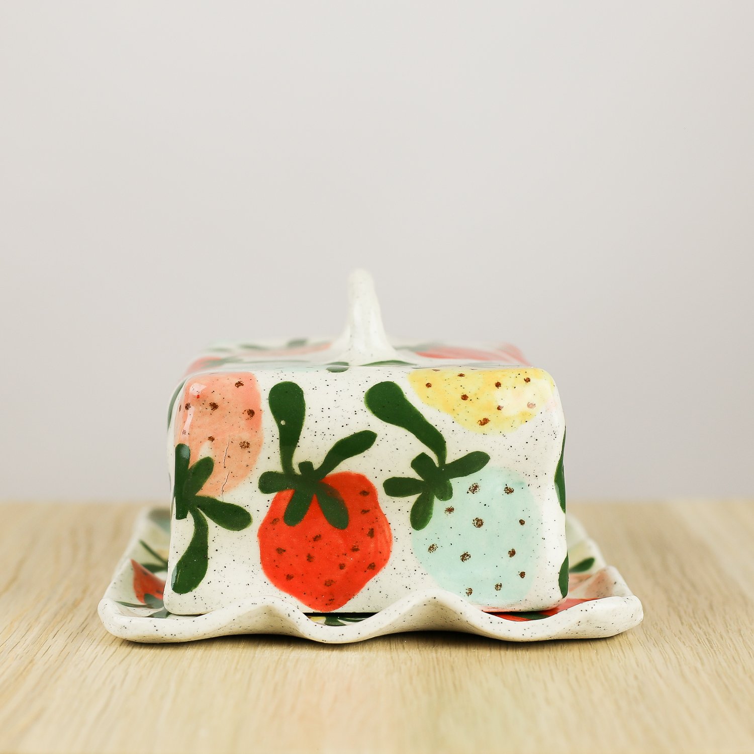 Handmade ceramic butter dish with hand-painted strawberries , set on a white background.