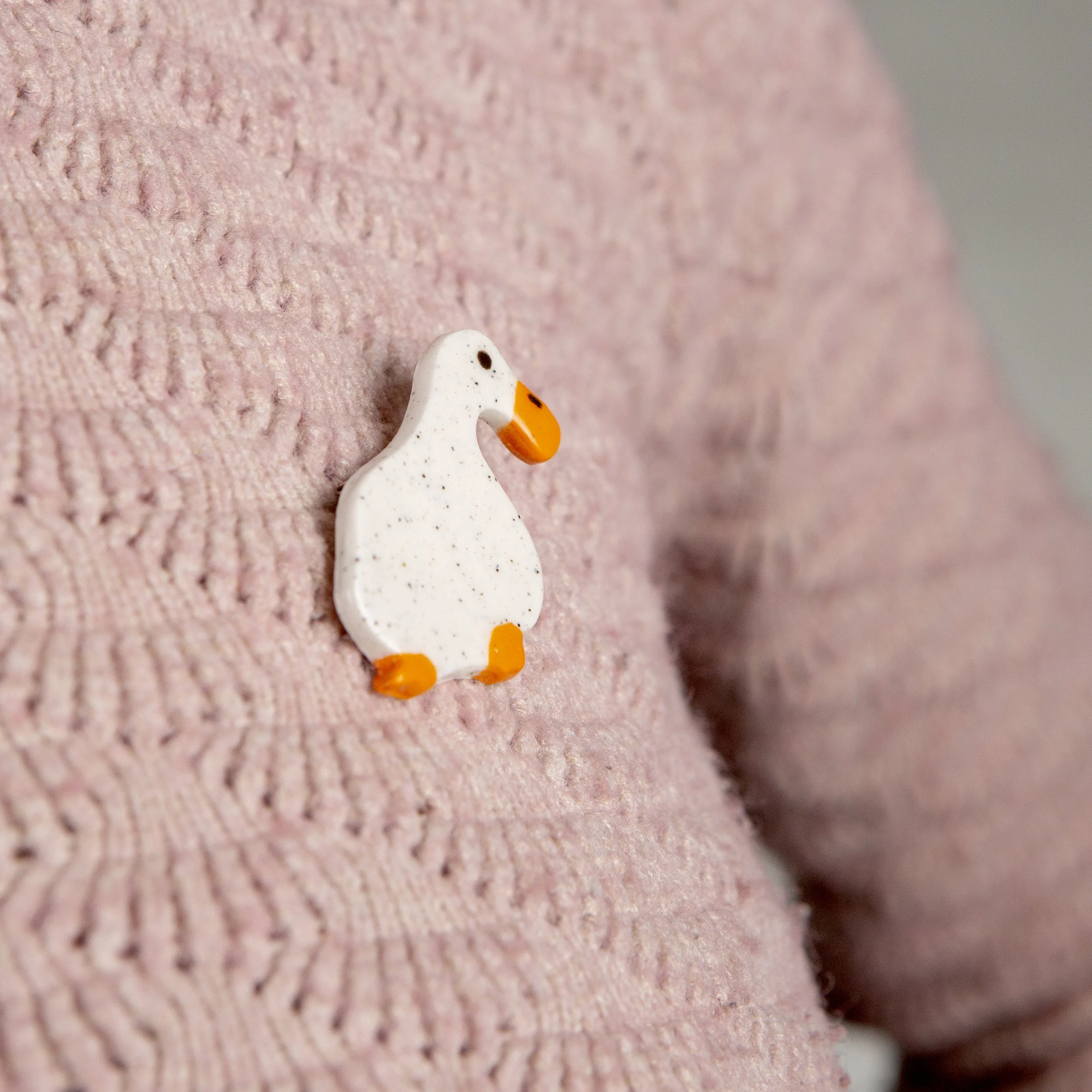 Handmade ceramic brooch with a glossy dreamer white duck, photographed on a neutral background