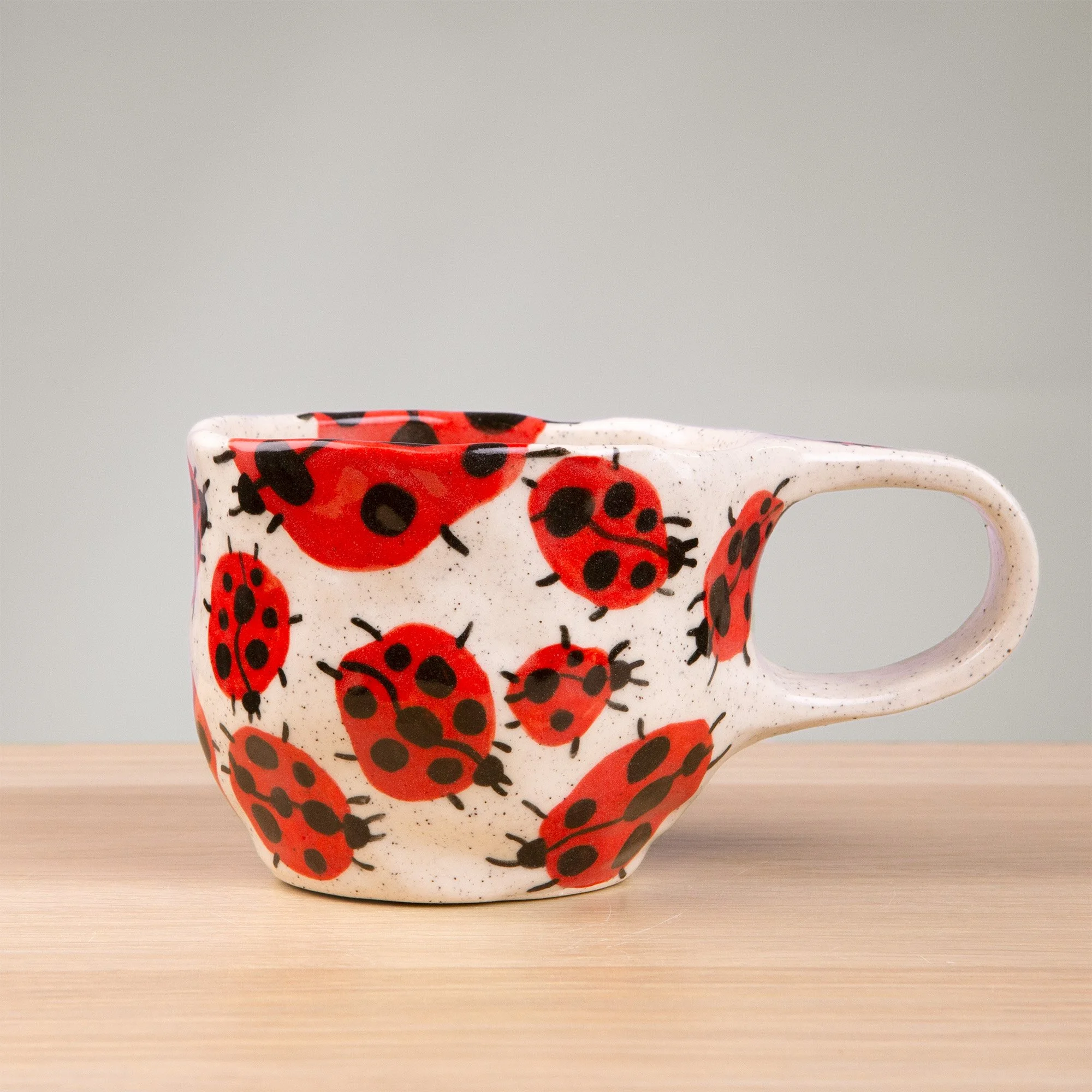 this handmade ceramic cup is alive with a loveliness of ladybugs, each one carefully hand-painted and scattered across the surface like tiny wanderers in a sunlit garden.
