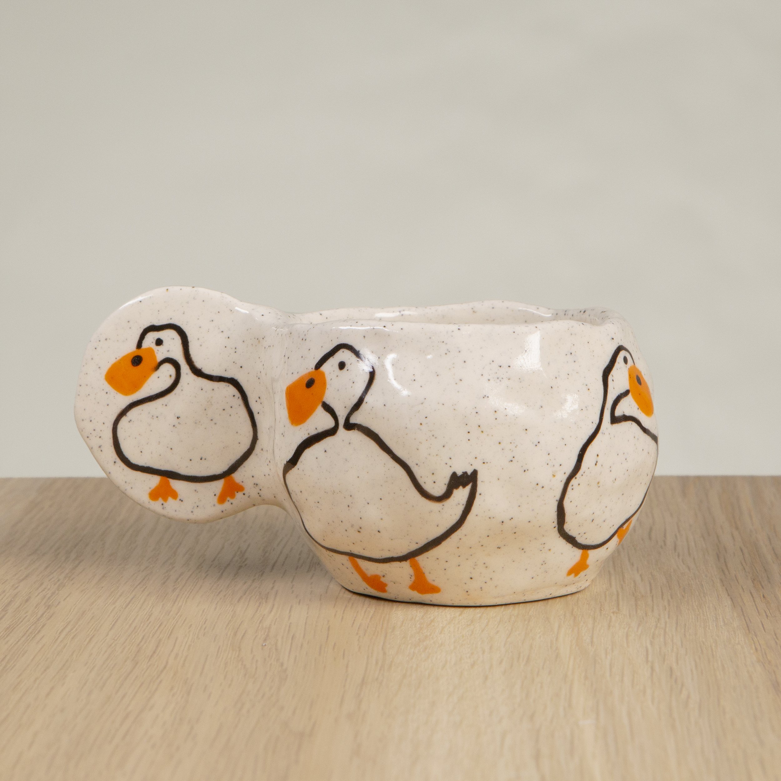 Handmade ceramic coffee cup with hand-painted loving ducks, crafted from speckled clay in Melbourne with a cute petal handle. Holds approximately 150ml.