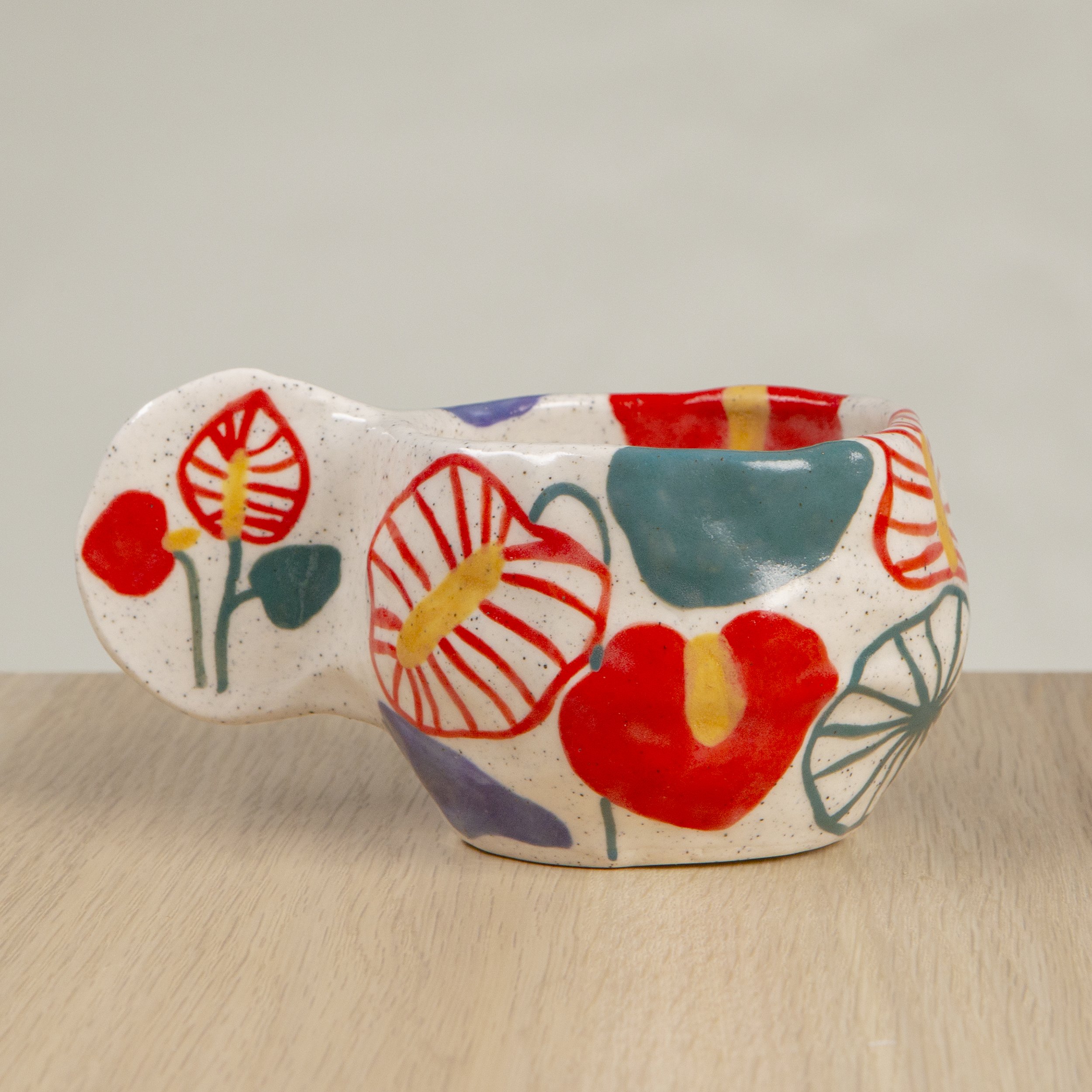 Handmade ceramic coffee cup with hand-painted anthurium flowers, crafted from speckled clay in Melbourne with a cute petal handle. Holds approximately 150ml.
