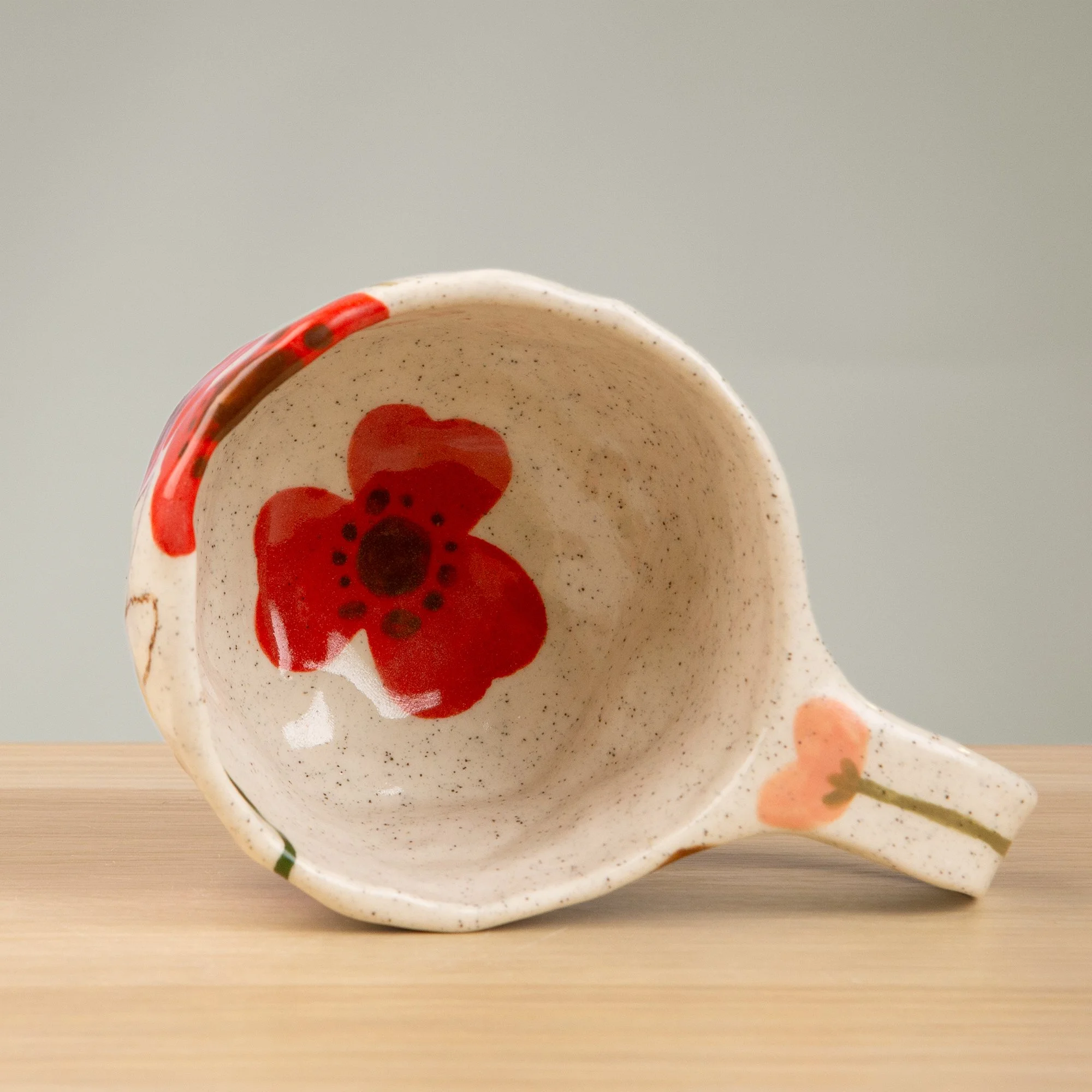 A soft garden in bloom, this handmade ceramic mug is adorned with hand-painted poppies, daisies and sweet pea flowers in a delicate, painterly style.