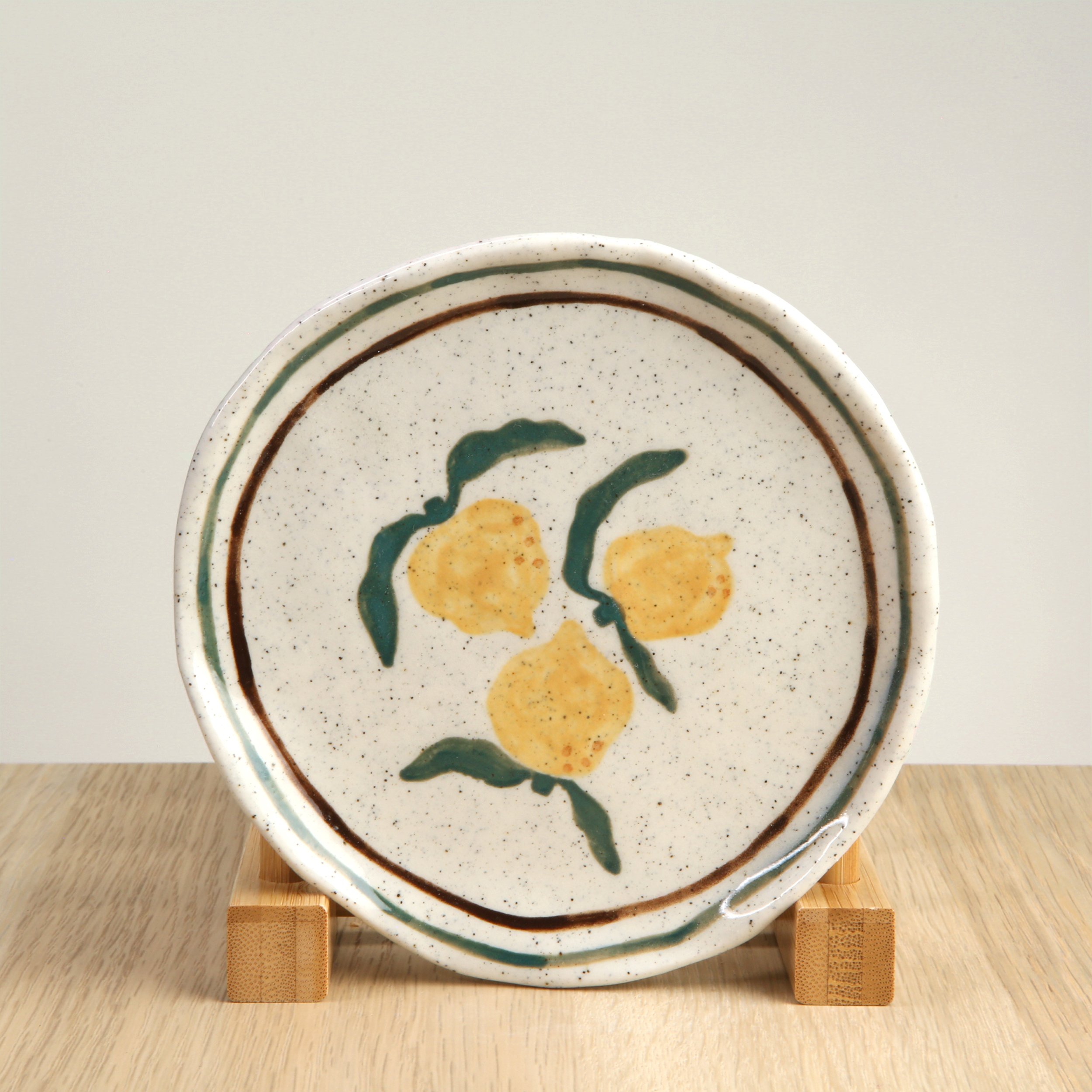 Ceramic 13.5cm saucer with handprinted lemons and 2 lines green and brown border