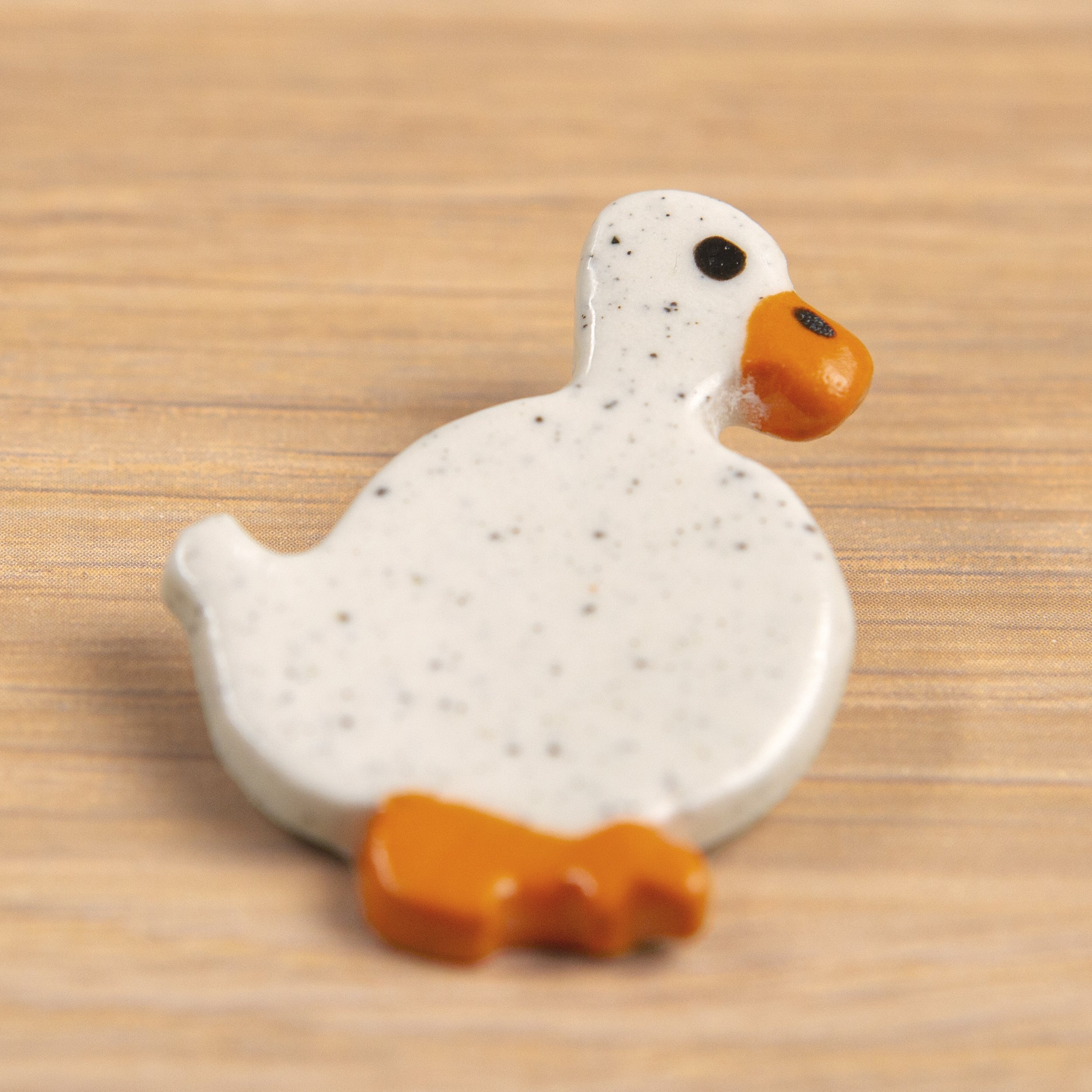 Handmade ceramic brooch with a glossy wandering white duck, photographed on a neutral background. (Copy)