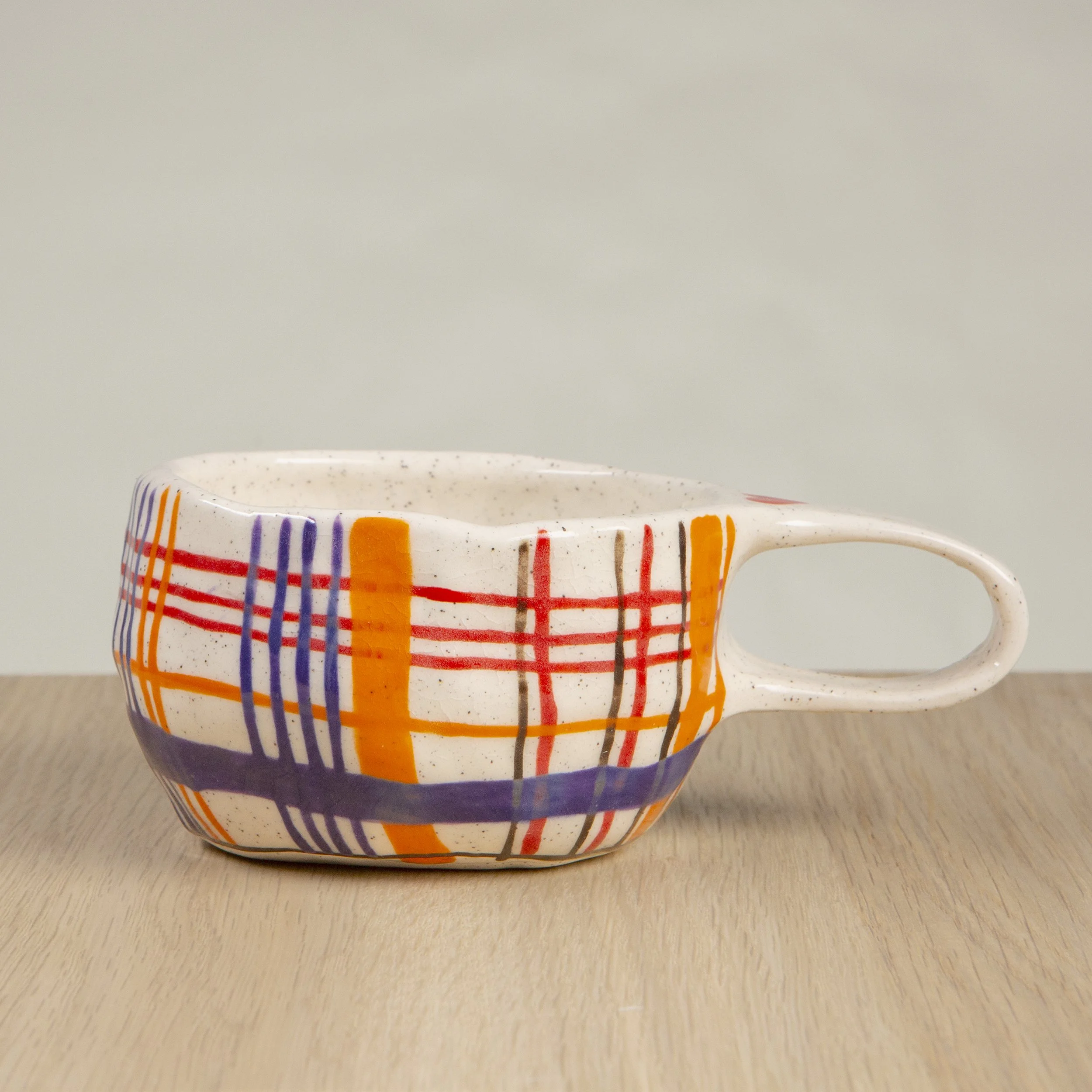 Handmade ceramic coffee cup with hand-painted orange/red/blue/brown check, crafted from speckled clay in Melbourne. Holds approximately 150ml.