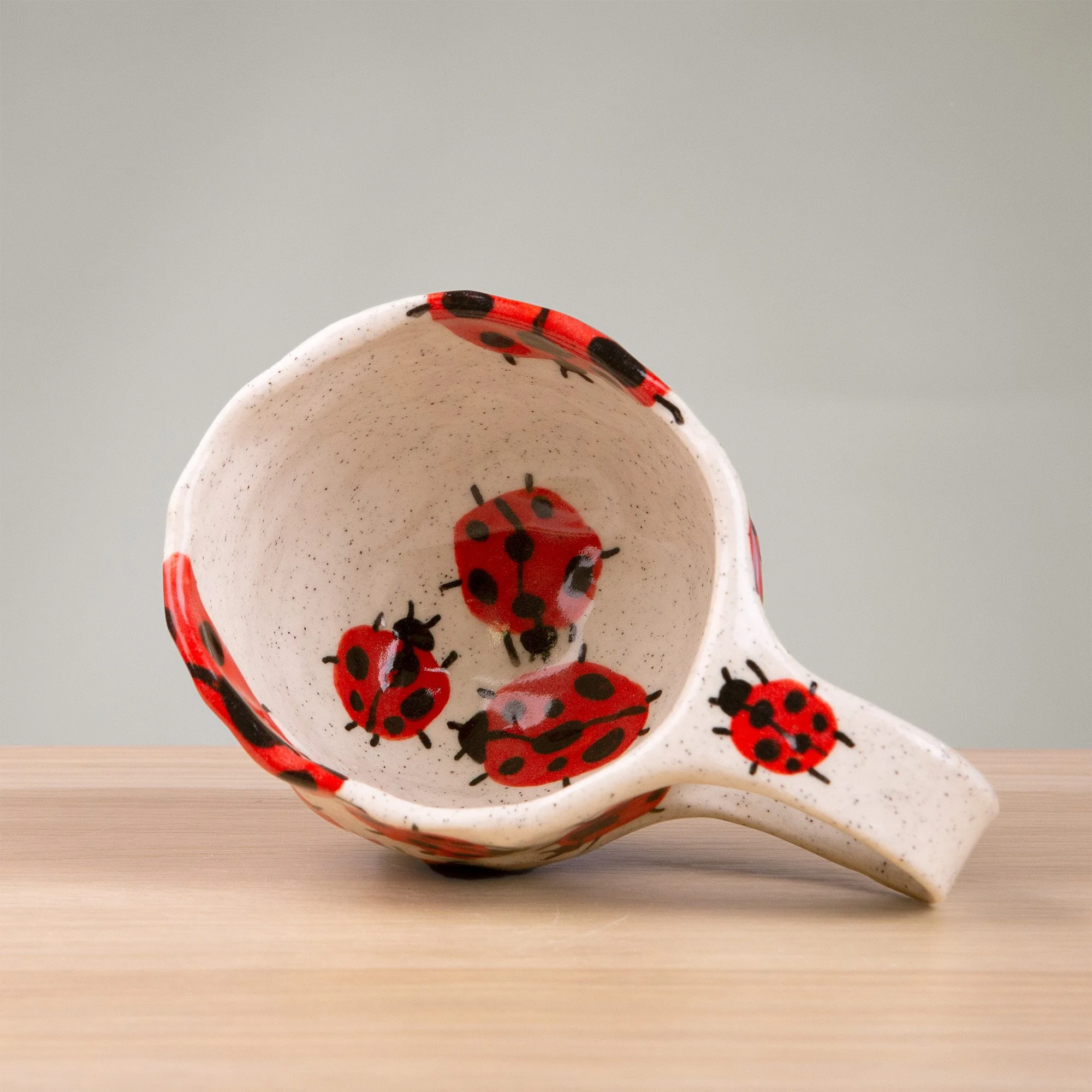 this handmade ceramic cup is alive with a loveliness of ladybugs, each one carefully hand-painted and scattered across the surface like tiny wanderers in a sunlit garden.