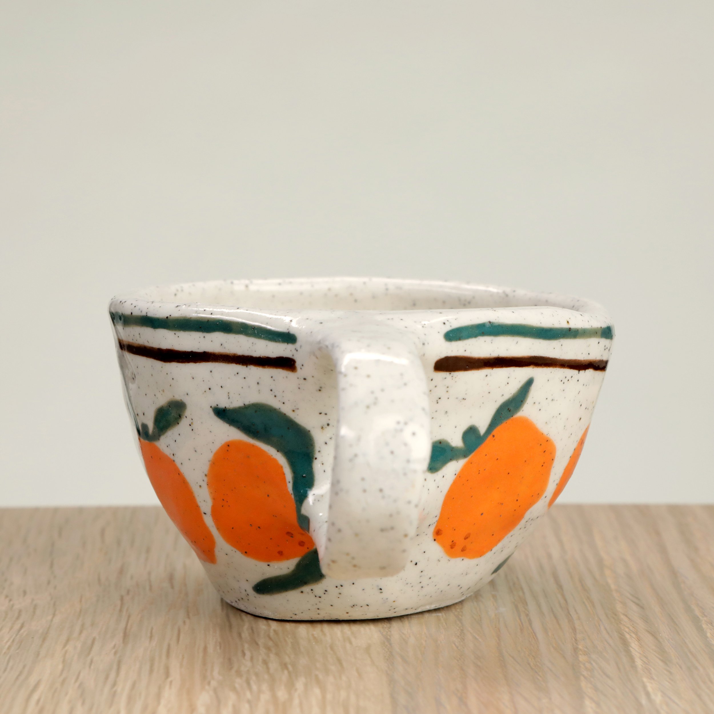 Handmade ceramic coffee cup with hand-painted mandarins & 2 lines border, crafted from speckled clay in Melbourne. Holds approximately 150ml.