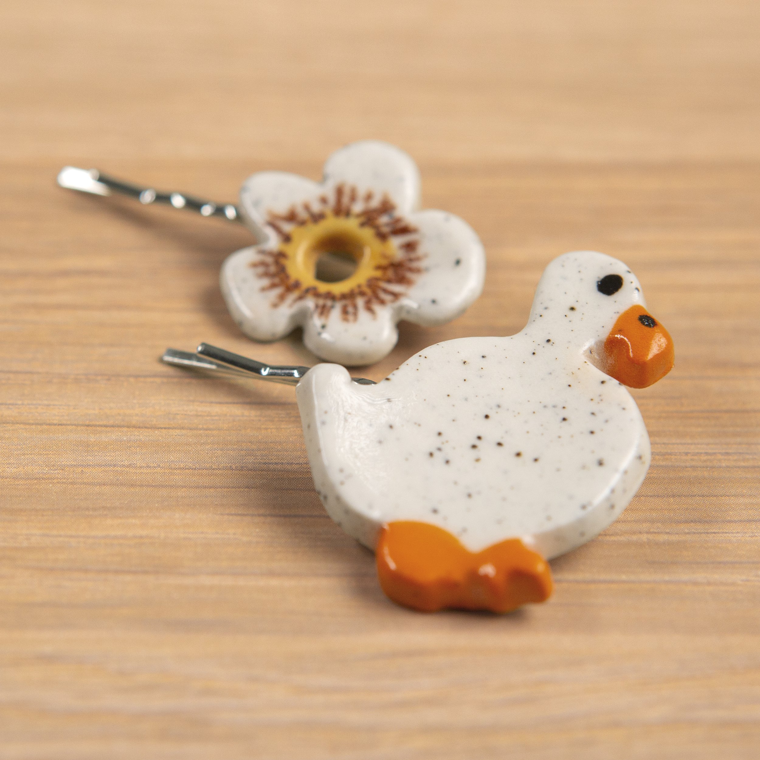 A set of two ceramic hair pins – one white flower and the other wandering white duck, handmade and painted.