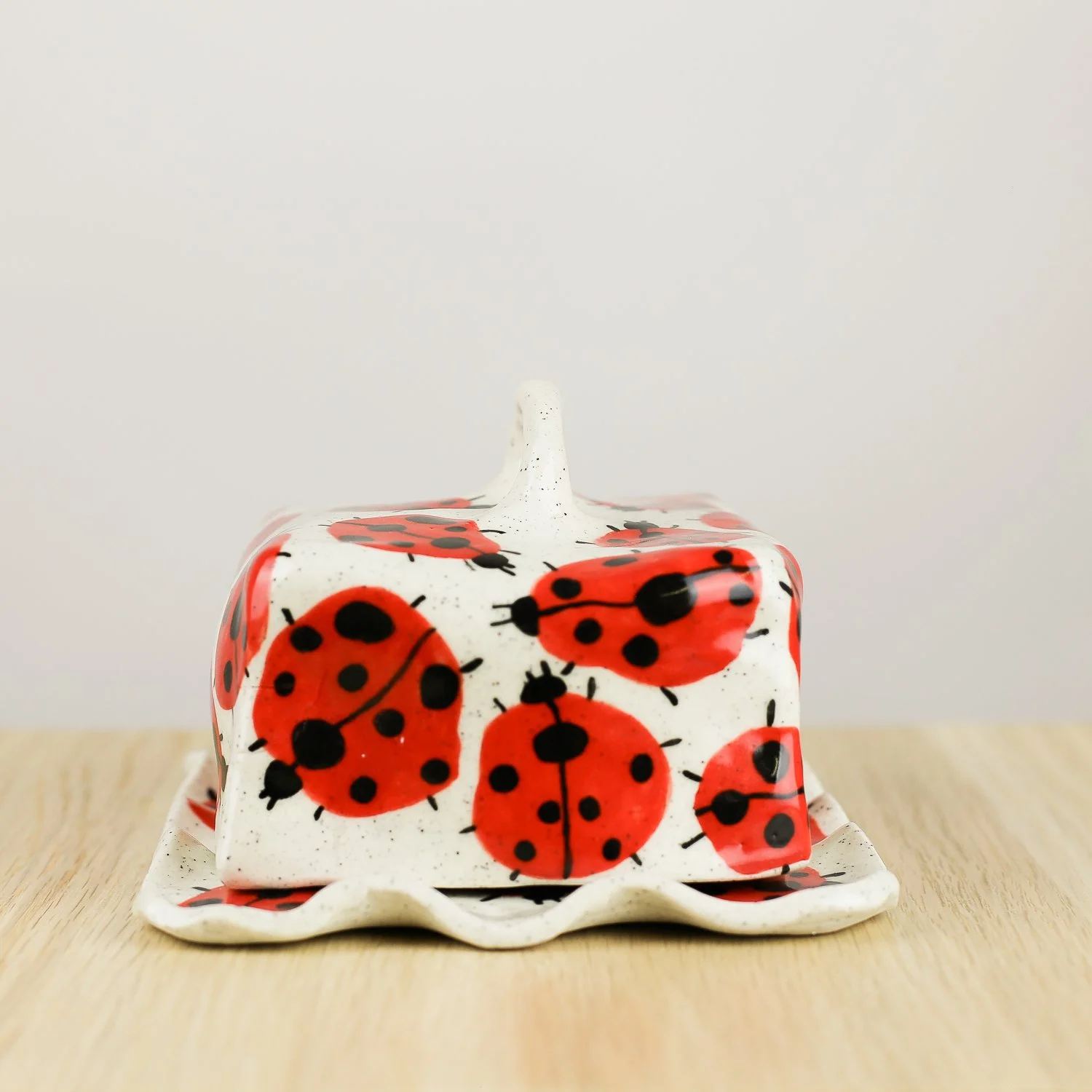 Handmade ceramic butter dish featuring a loveliness of hand-painted ladybugs. Fits 450–500g butter. A unique, whimsical piece to brighten your table.