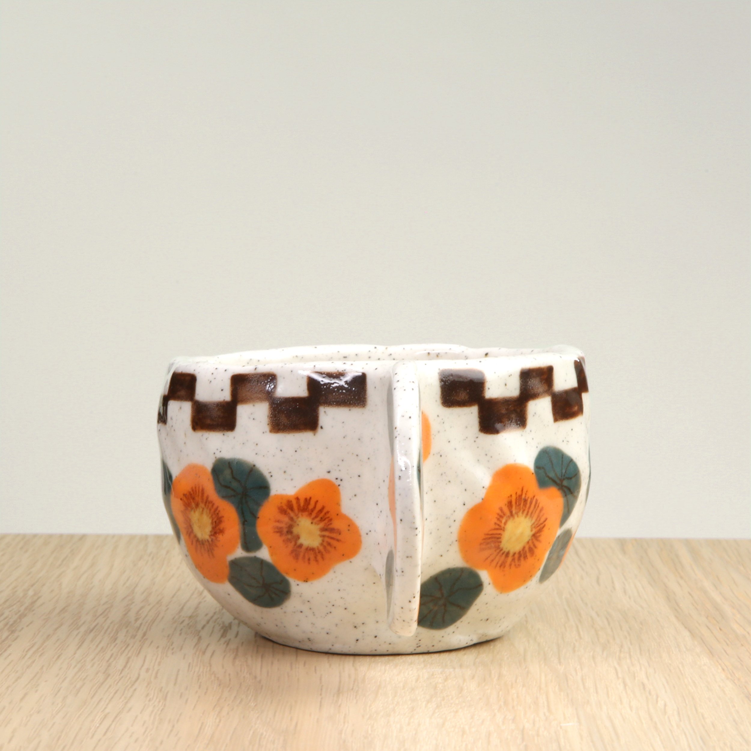 Handmade ceramic coffee cup with hand-painted nasturtium flowers & a chocolate check border, crafted from speckled clay in Melbourne. Holds approximately 150ml.