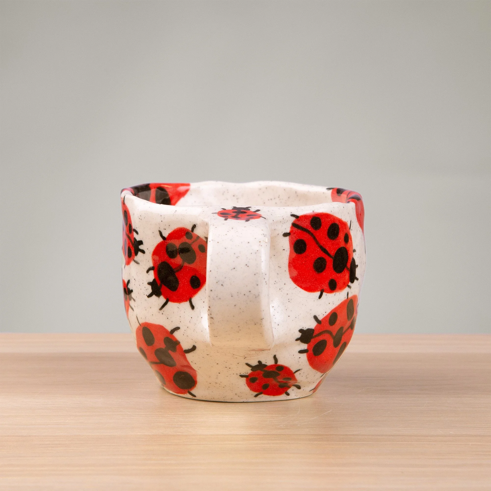 this handmade ceramic cup is alive with a loveliness of ladybugs, each one carefully hand-painted and scattered across the surface like tiny wanderers in a sunlit garden.