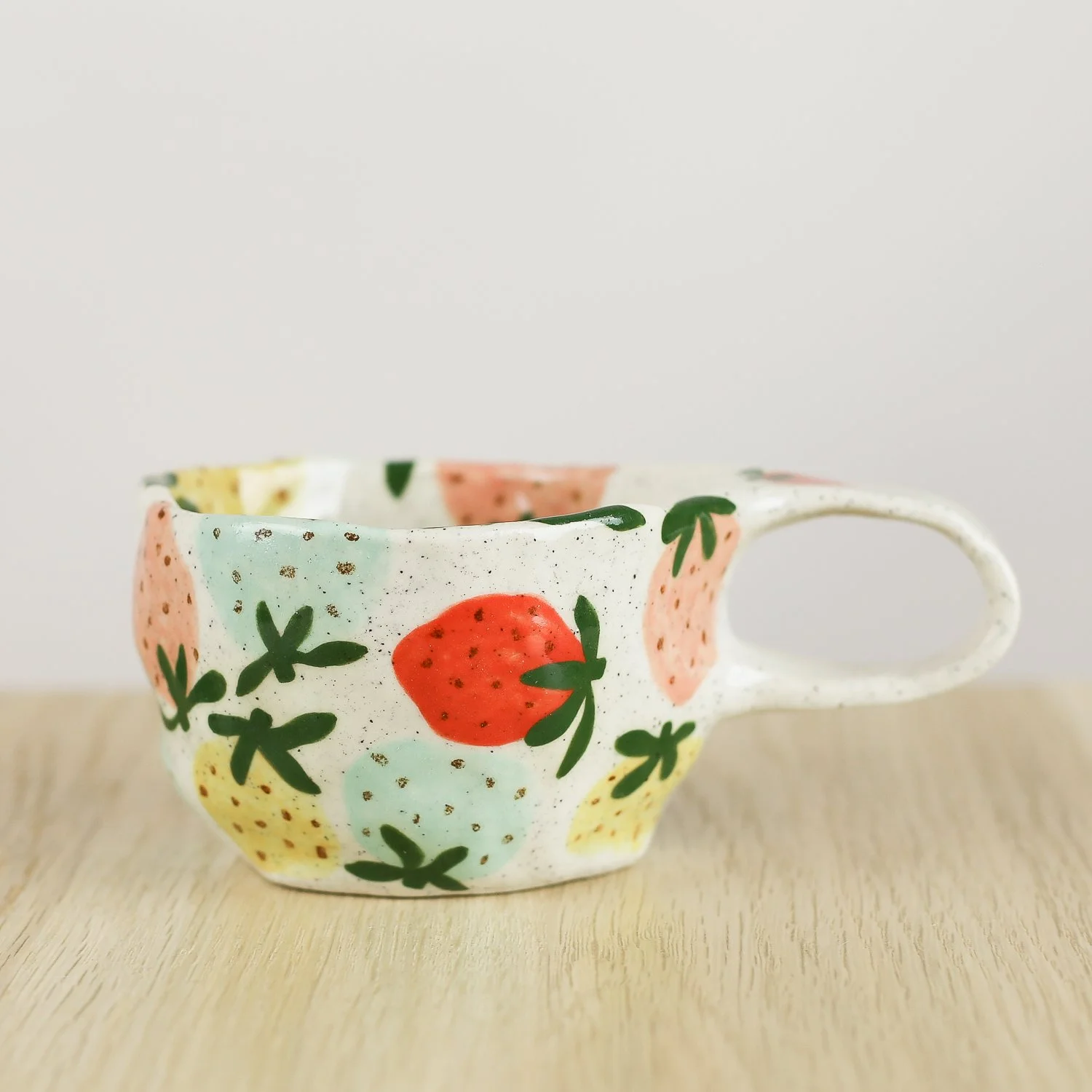 Handmade ceramic cup with hand-painted strawberries in red, pink, yellow and blue. Holds 150ml. A unique, playful coffee cup for everyday use.