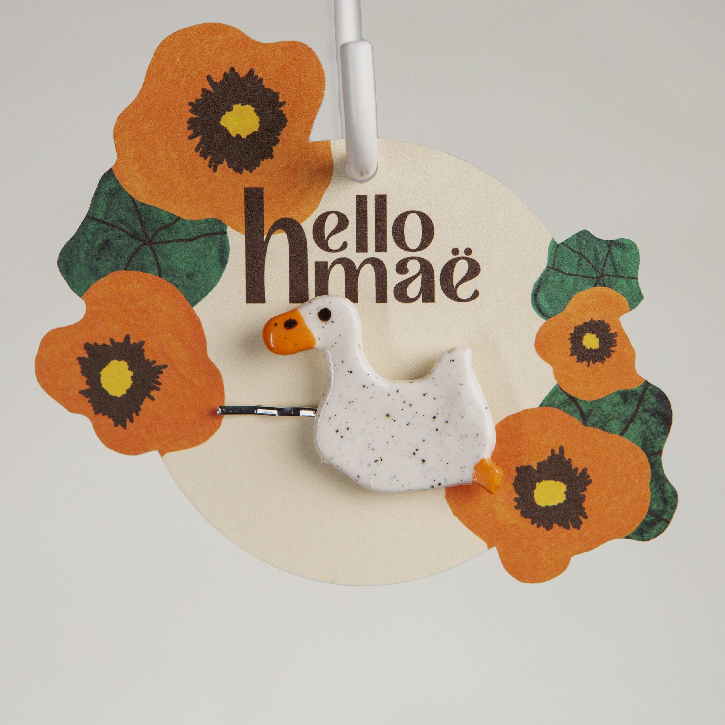 Handmade ceramic hair pin with a glossy swimming white duck, photographed on a neutral background.