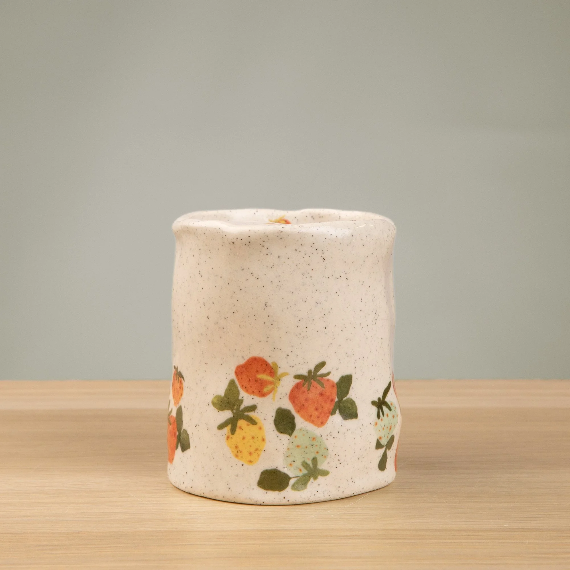 Handmade speckled ceramic strawberry dream travel cup decorated with sweet red, pink, yellow and blue strawberries