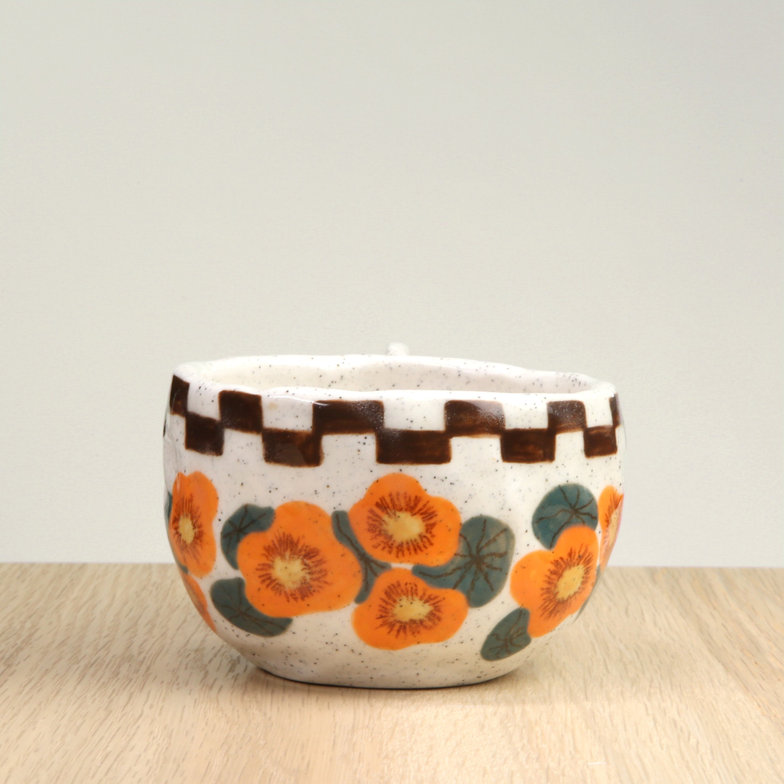 Handmade ceramic coffee cup with hand-painted nasturtium flowers & a chocolate check border, crafted from speckled clay in Melbourne. Holds approximately 150ml.