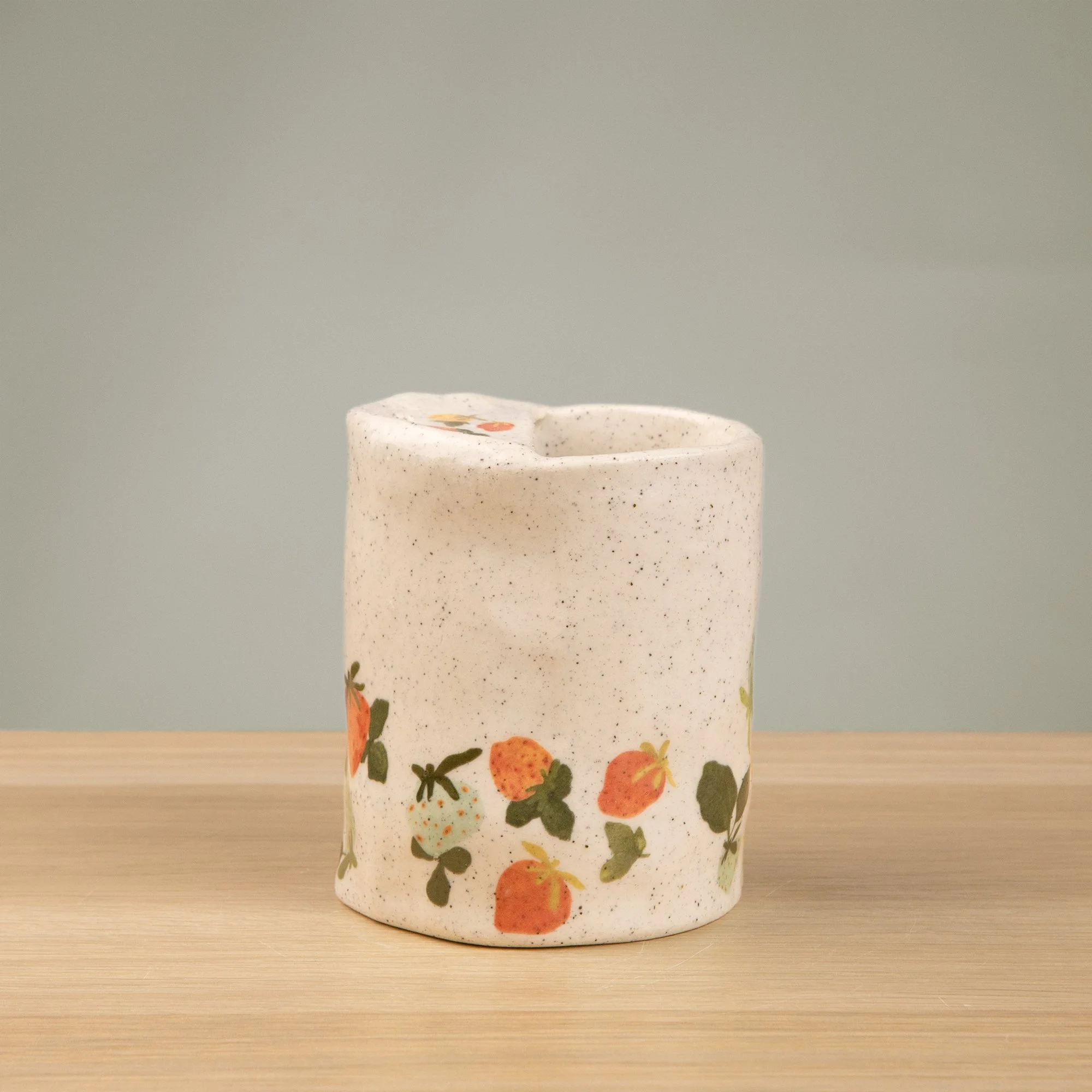 Handmade speckled ceramic strawberry dream travel cup decorated with sweet red, pink, yellow and blue strawberries