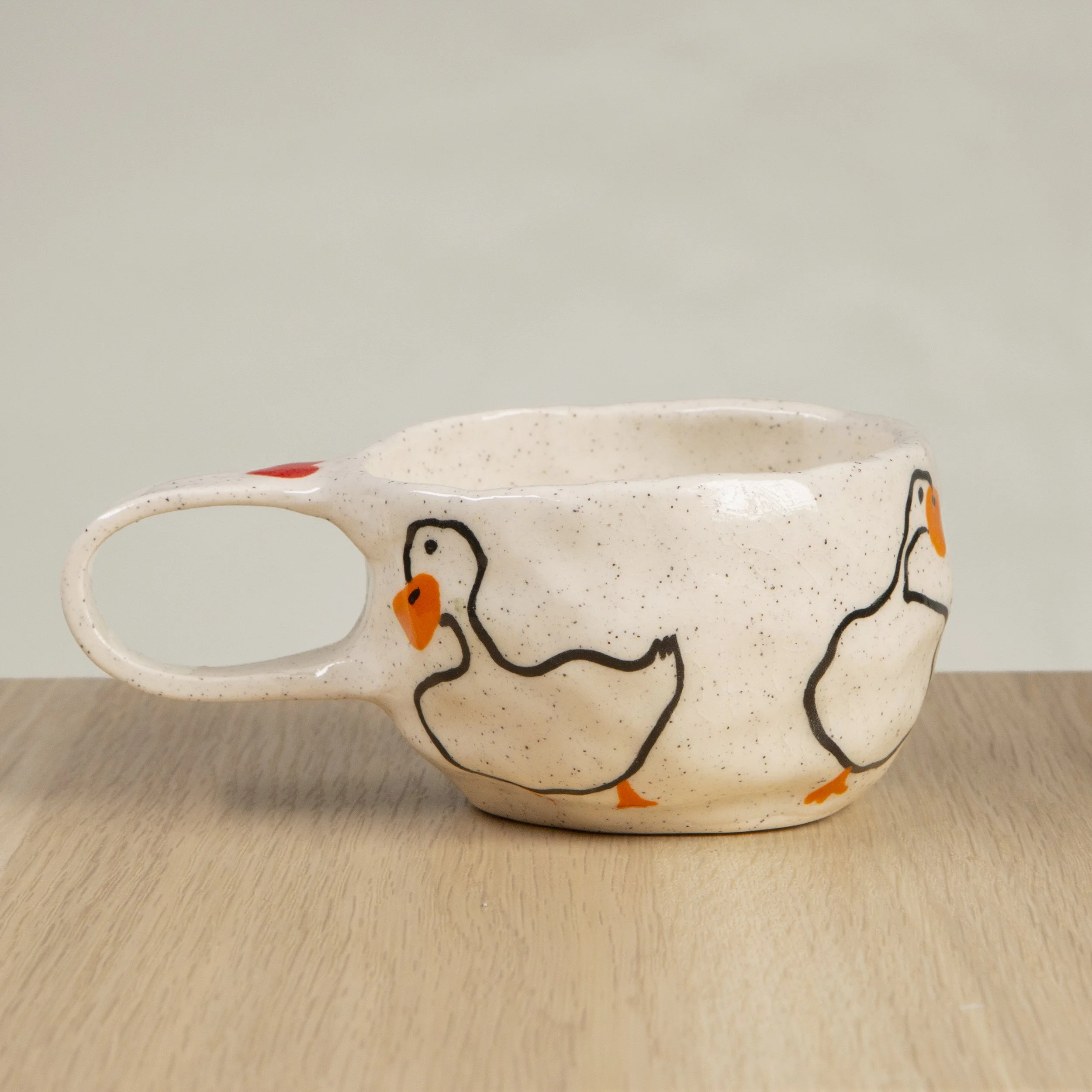 Handmade ceramic coffee cup with hand-painted loving ducks, crafted from speckled clay in Melbourne. Holds approximately 150ml.