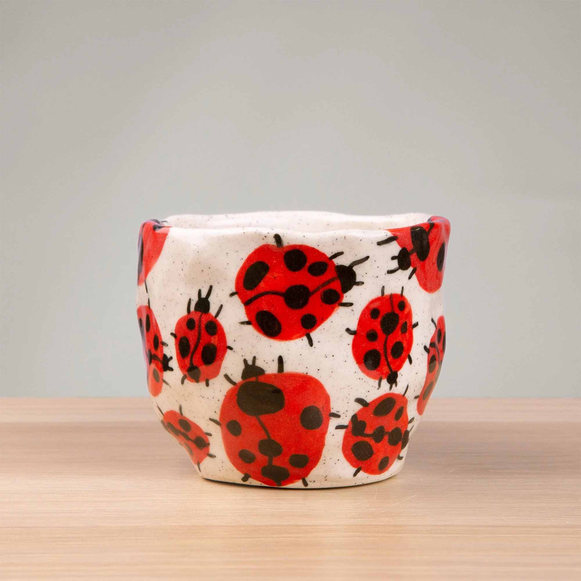 this handmade ceramic cup is alive with a loveliness of ladybugs, each one carefully hand-painted and scattered across the surface like tiny wanderers in a sunlit garden.