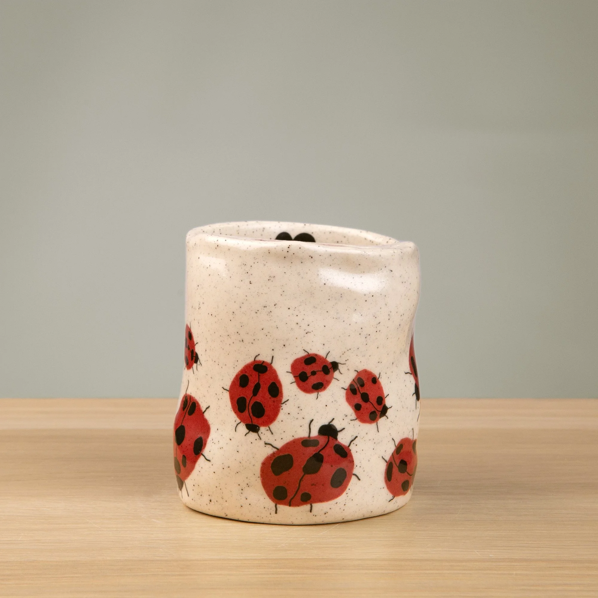 Handmade speckled ceramic Loveliness travel cup decorated with cheerful red ladybugs