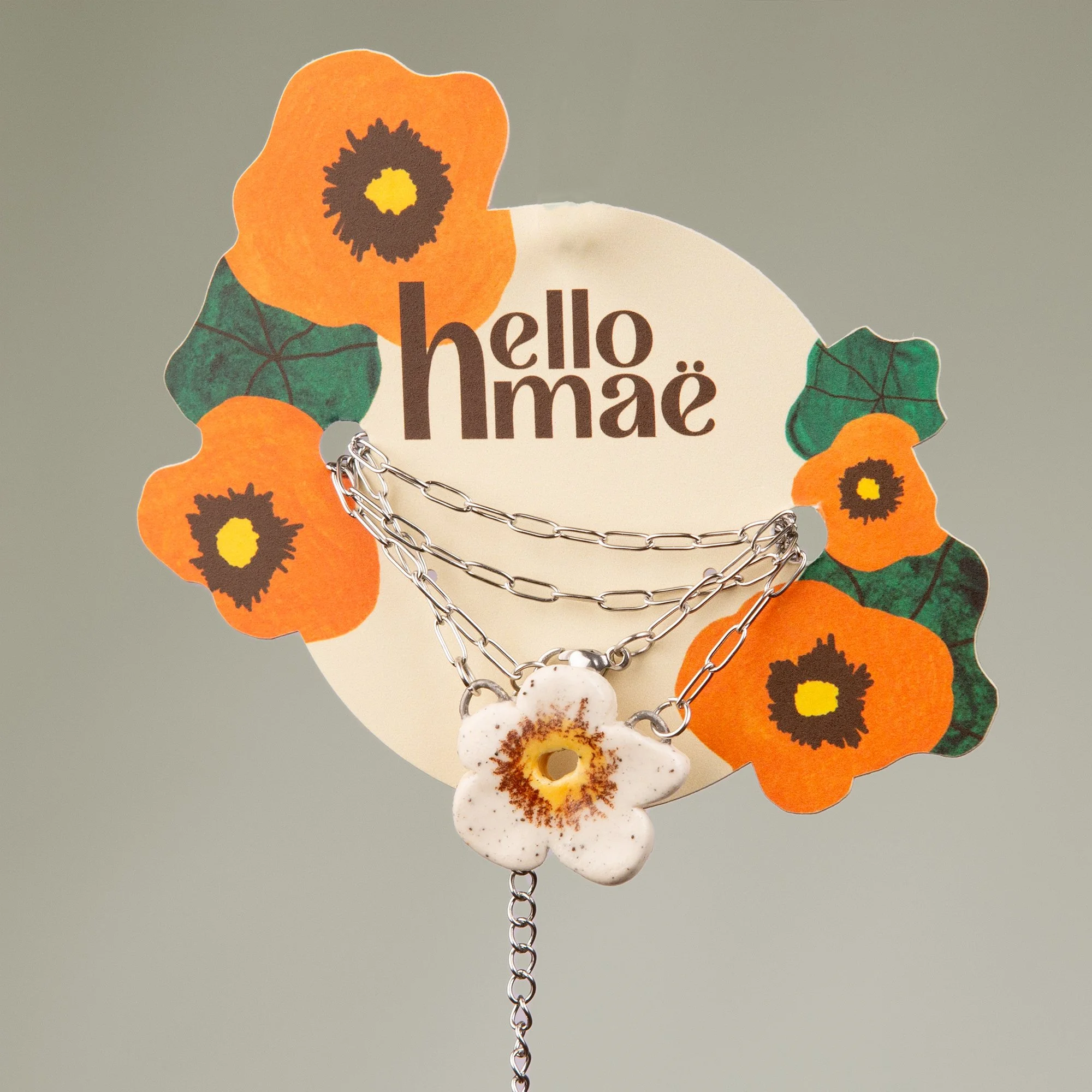 Handmade ceramic white flower necklace featuring a playful hand-painted white flower pendant on a silver-coloured chain.