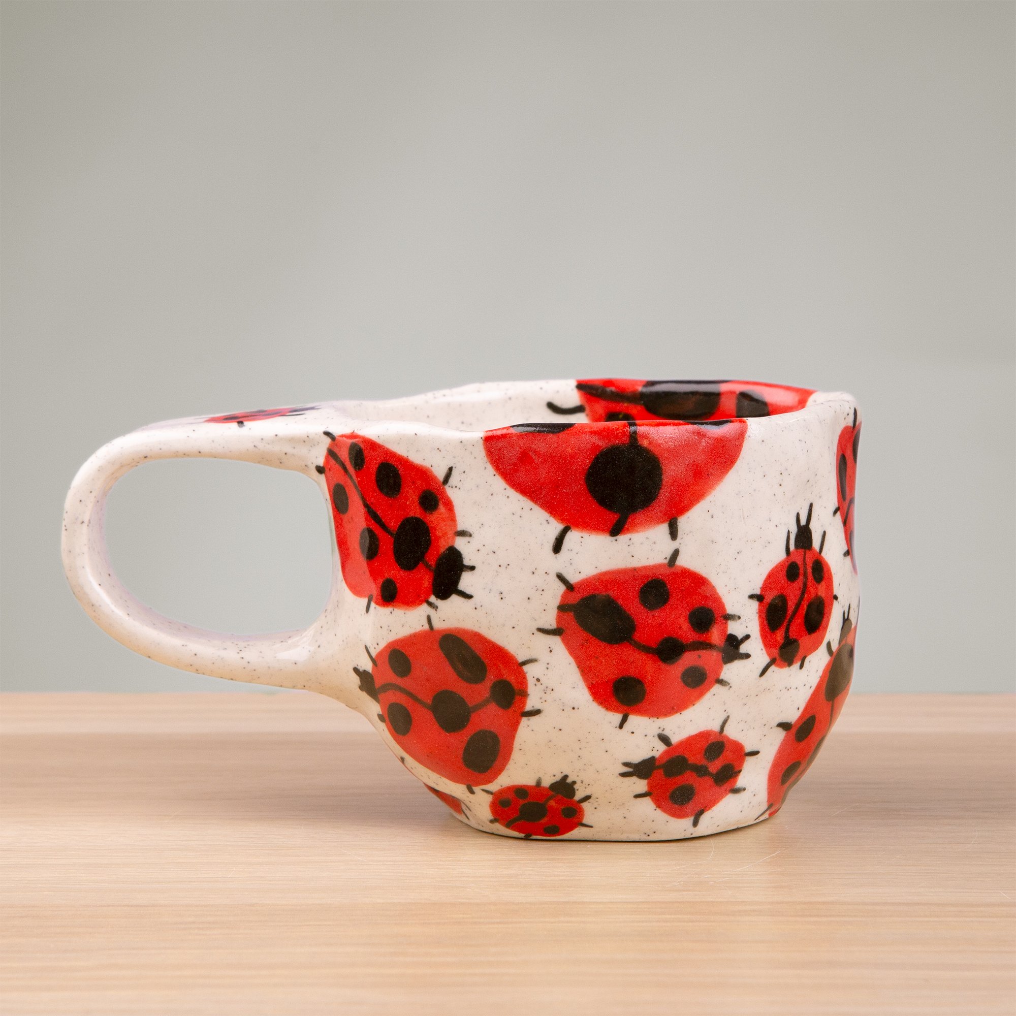 this handmade ceramic cup is alive with a loveliness of ladybugs, each one carefully hand-painted and scattered across the surface like tiny wanderers in a sunlit garden.
