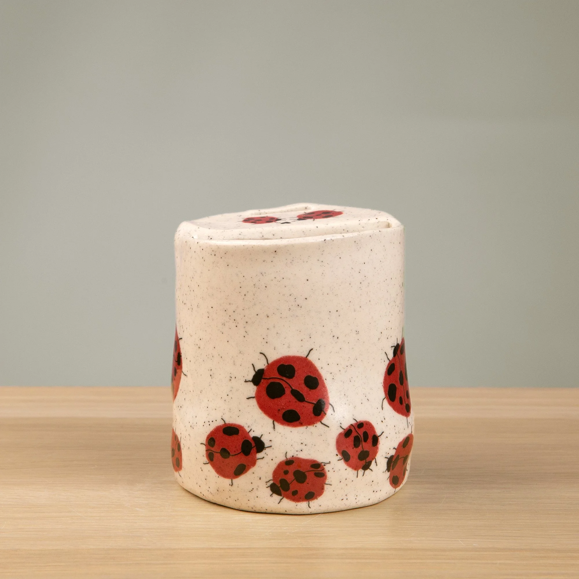Handmade speckled ceramic Loveliness travel cup decorated with cheerful red ladybugs