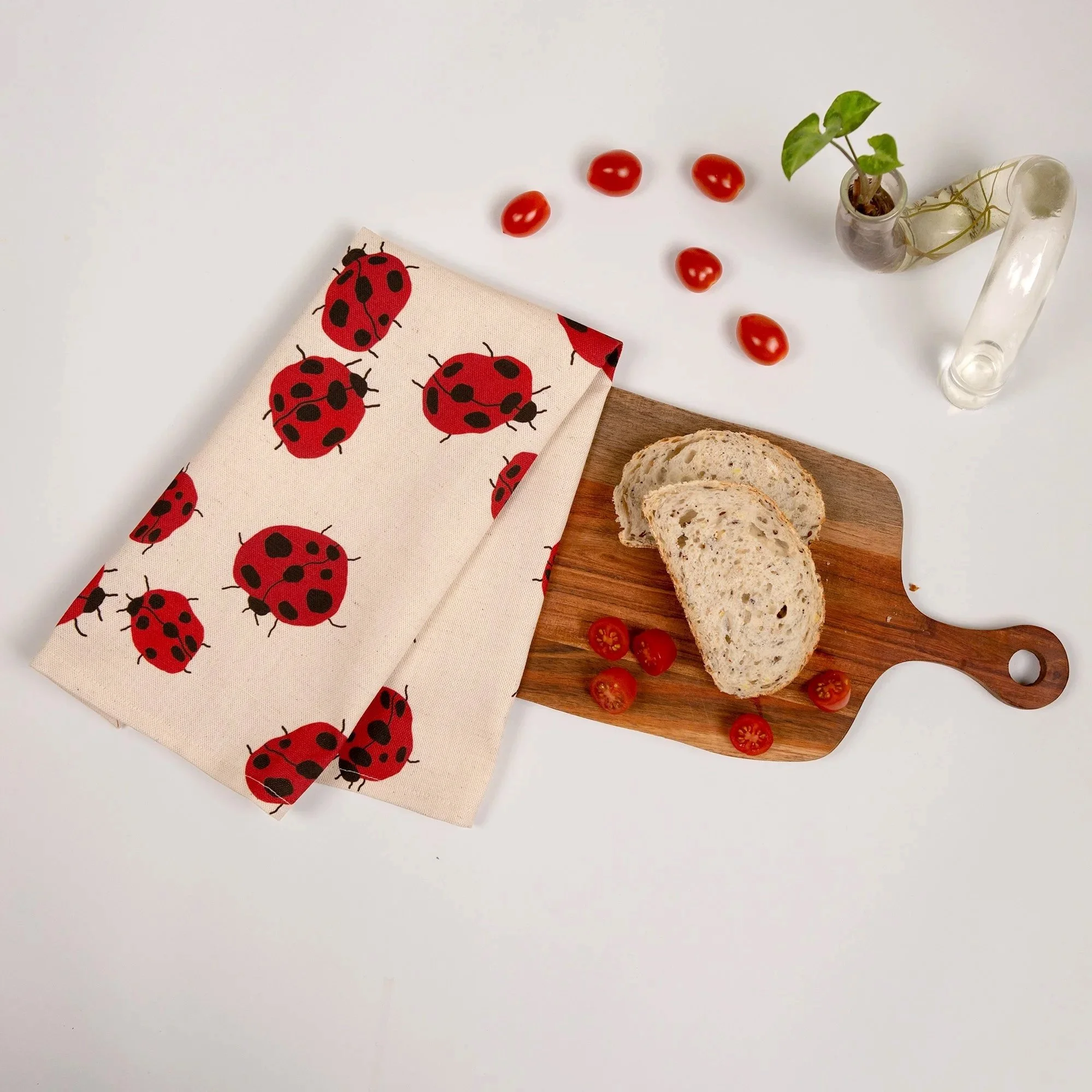 Colourful Loveliness tea towel featuring a playful print of red ladybugs and garden-inspired details.