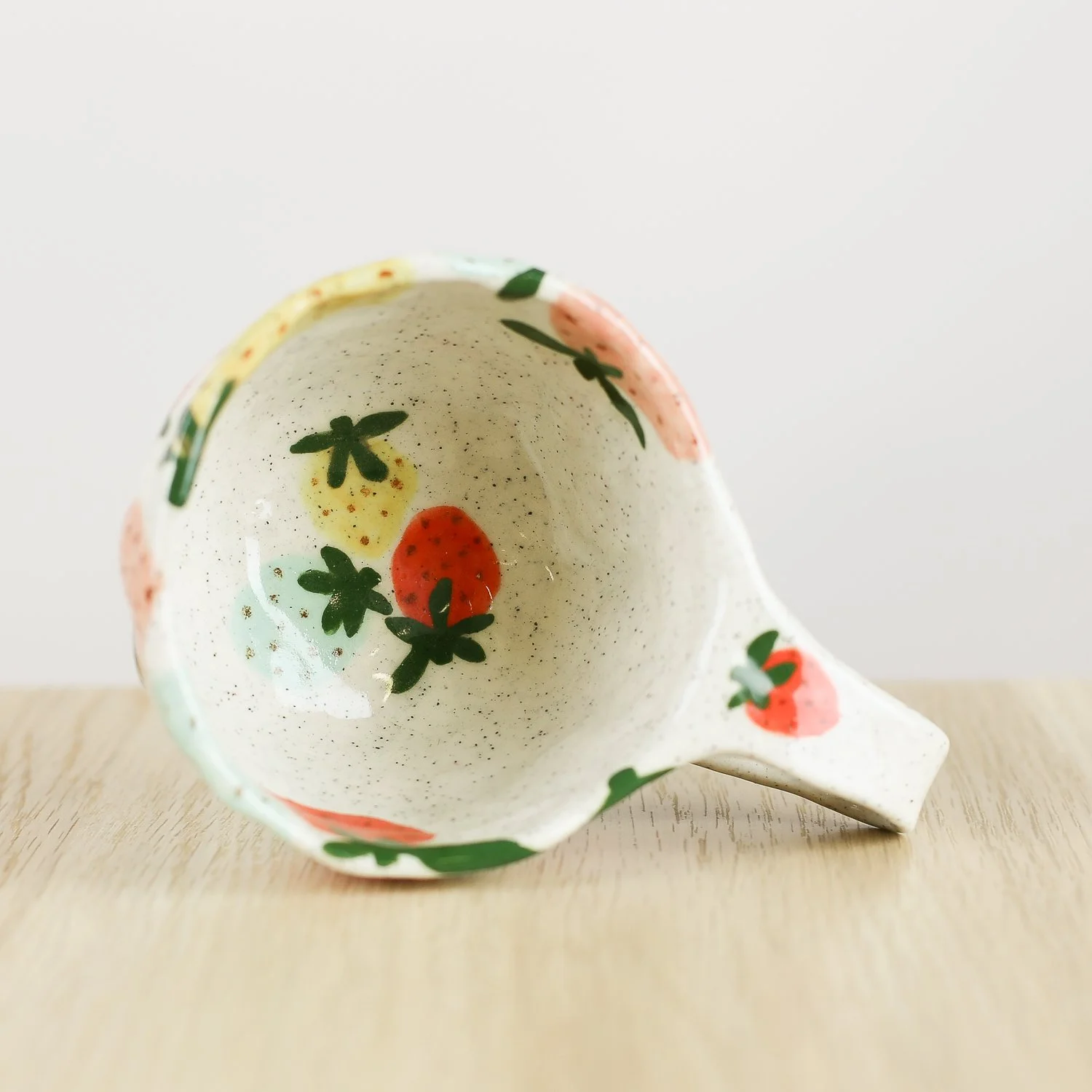 Handmade ceramic cup with hand-painted strawberries in red, pink, yellow and blue. Holds 150ml. A unique, playful coffee cup for everyday use.