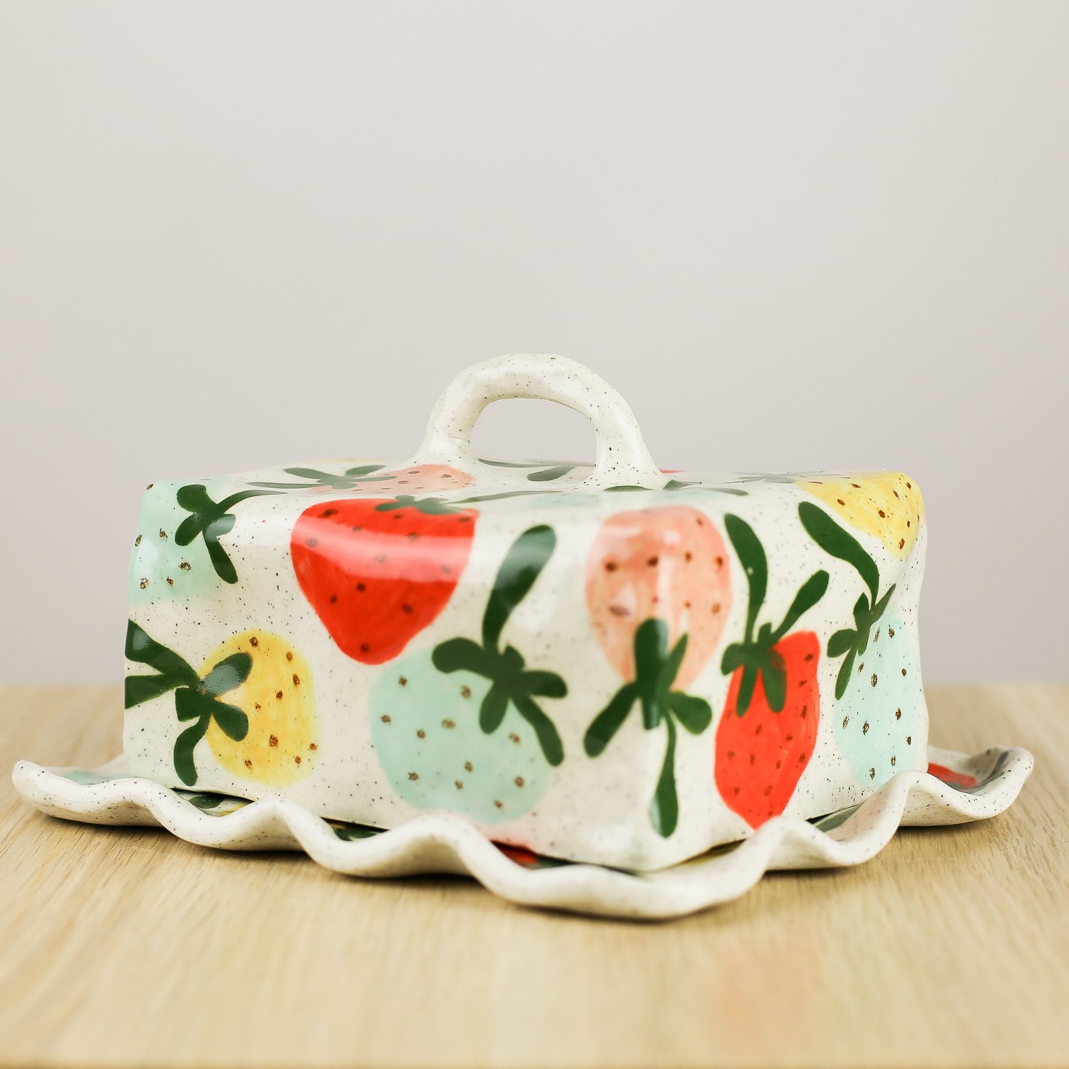 Handmade ceramic butter dish with hand-painted strawberries , set on a white background.