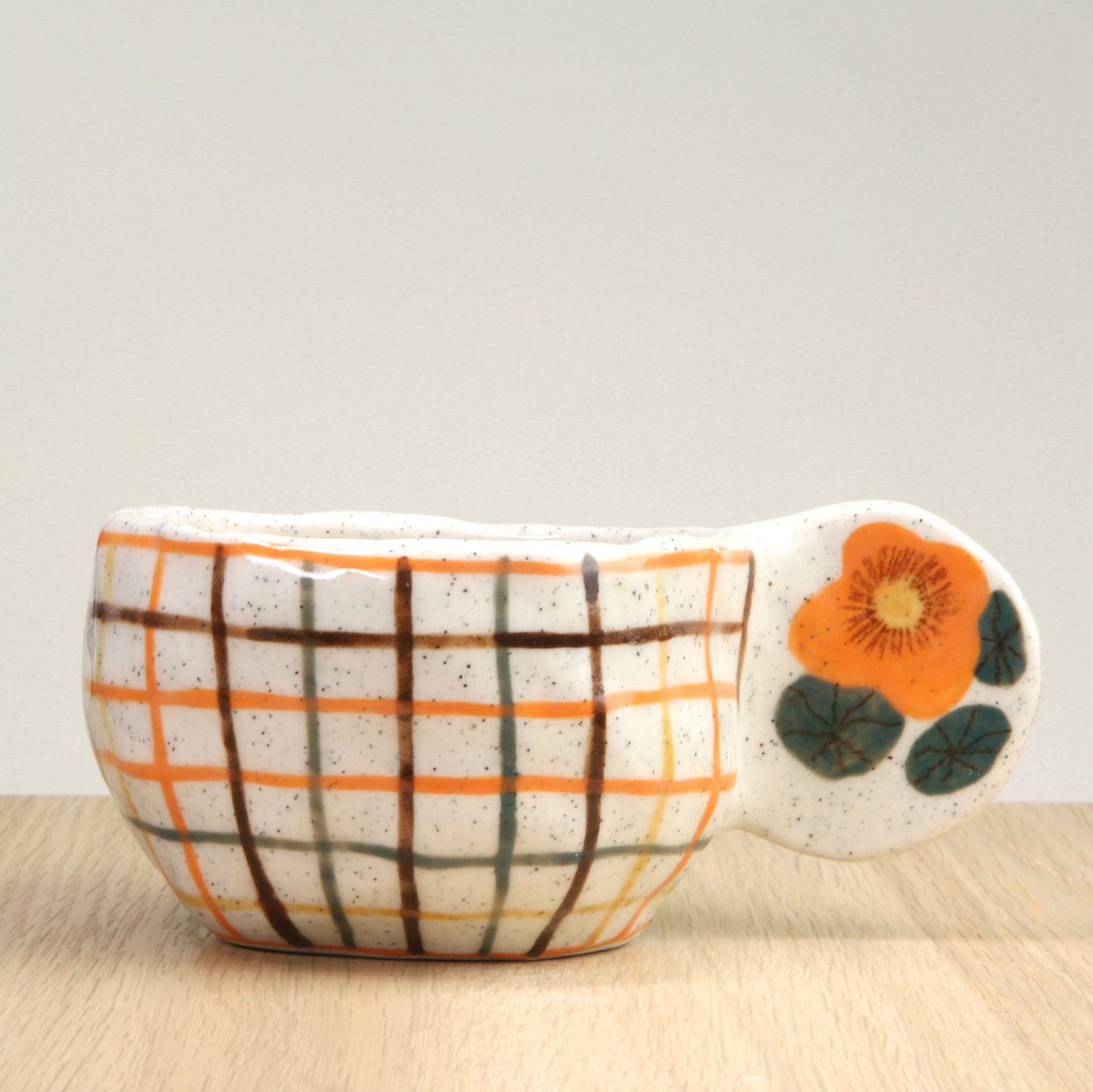 Handmade ceramic coffee cup with hand-painted orange check, crafted from speckled clay in Melbourne. Holds approximately 150ml.