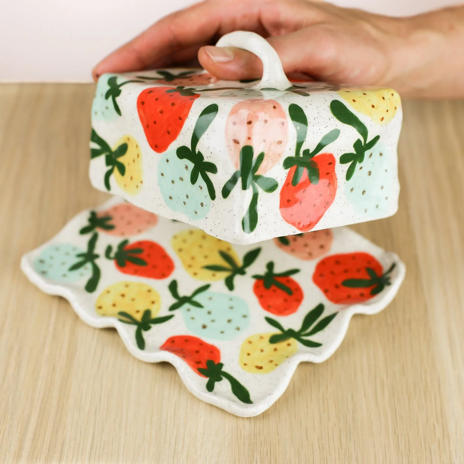 Handmade ceramic butter dish with hand-painted strawberries , set on a white background.