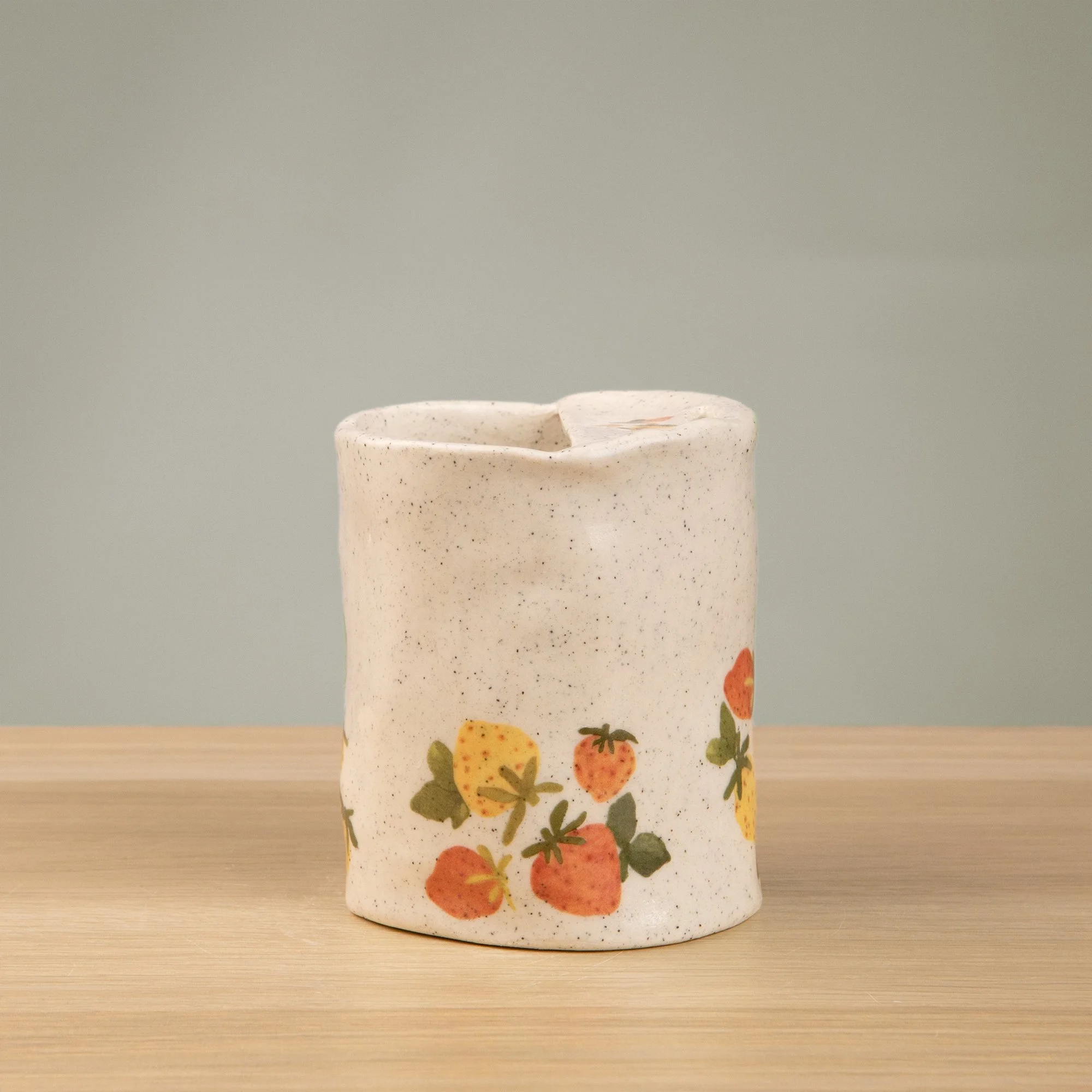 Handmade speckled ceramic strawberry dream travel cup decorated with sweet red, pink, yellow and blue strawberries