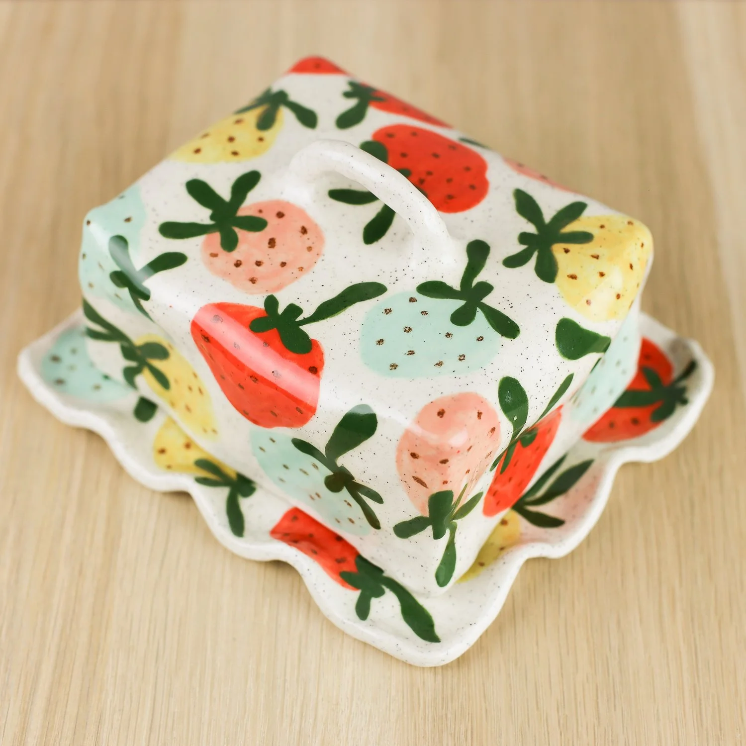 Handmade ceramic butter dish with hand-painted strawberries , set on a white background.