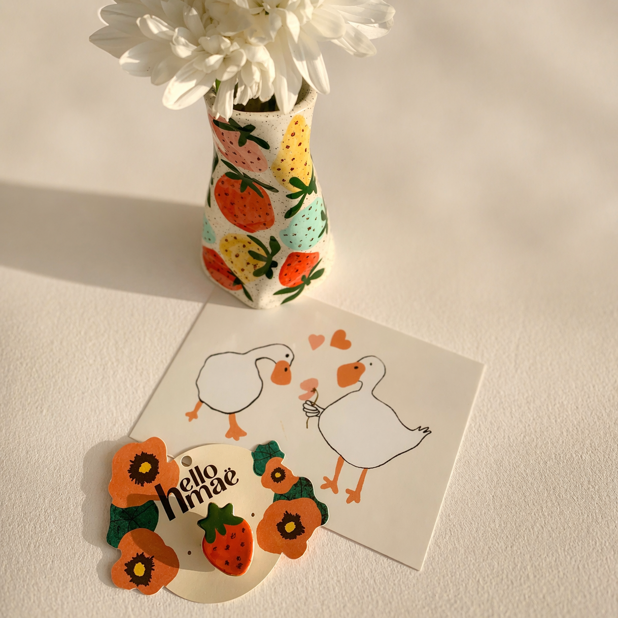 Handmade ceramic strawberry vase with matching strawberry brooch styled together on a soft, light background