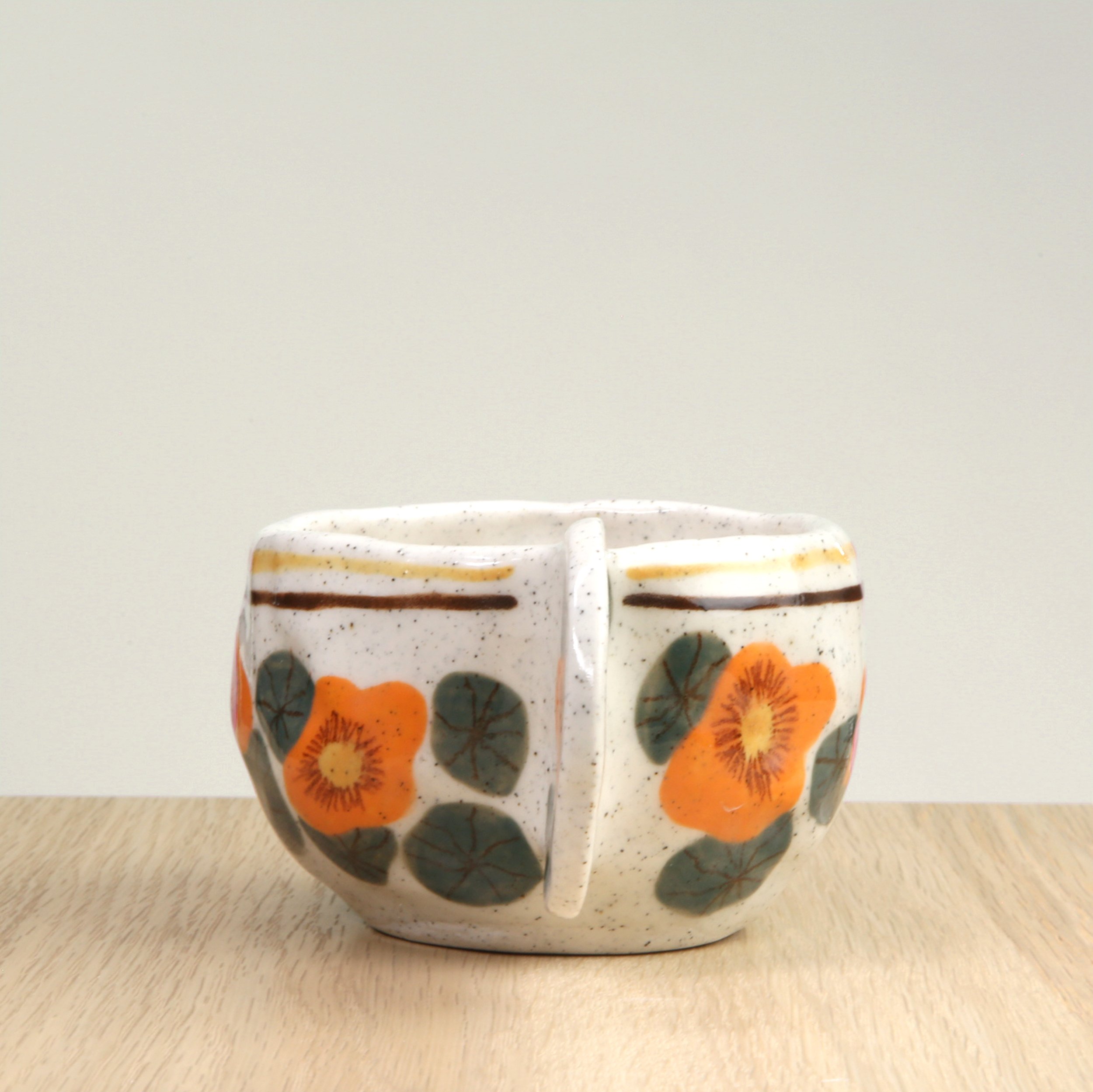 Handmade ceramic coffee cup with hand-painted nasturtium flowers & 2 lines border, crafted from speckled clay in Melbourne. Holds approximately 150ml.