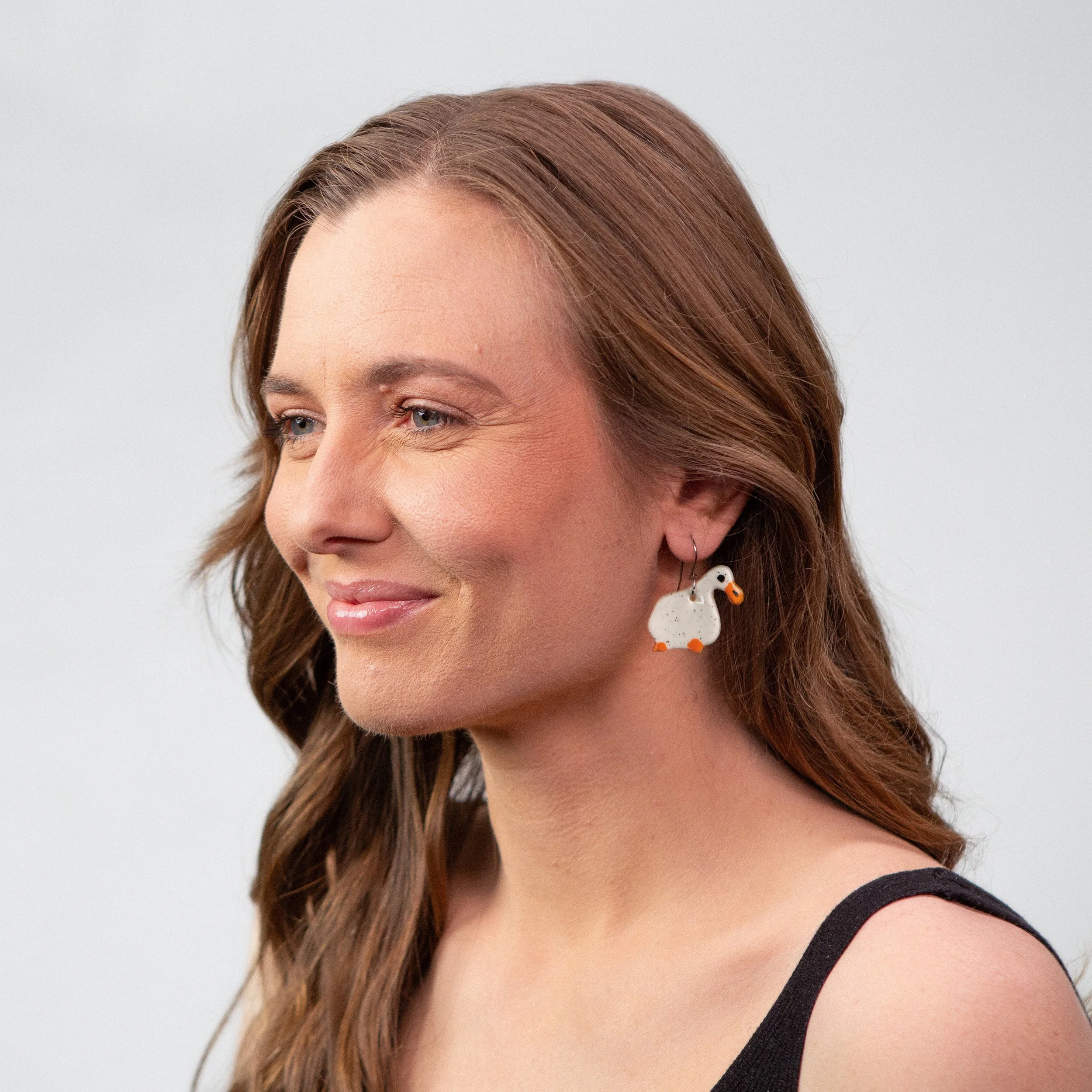 Handmade one-tier ceramic white ducks earrings with surgical steel hooks photographed on a neutral background.