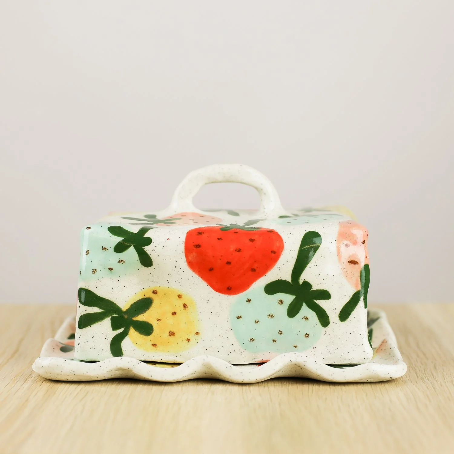 Handmade ceramic butter dish with hand-painted strawberries , set on a white background.