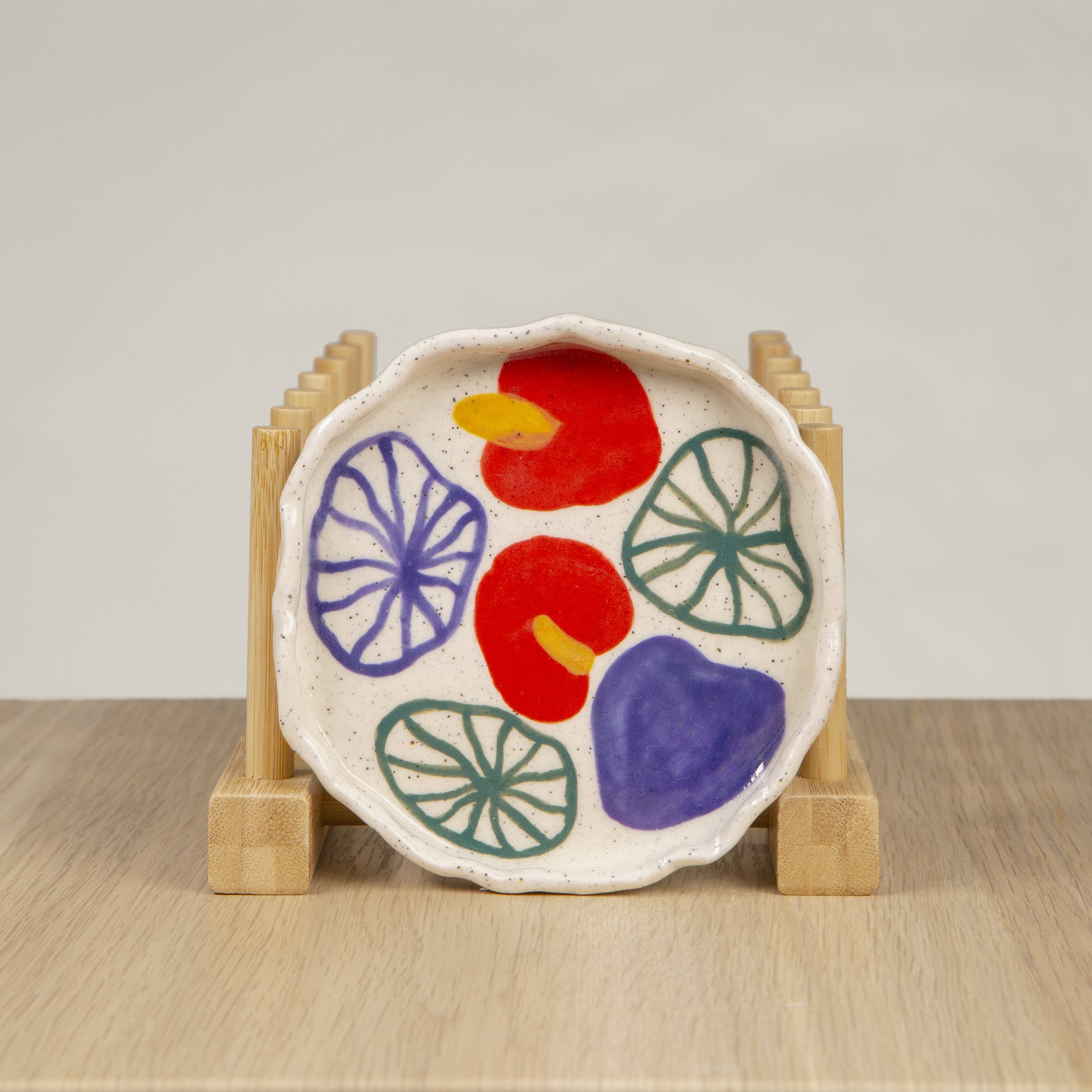 Round ceramic trinket dish featuring a hand-painted anthurium flower design on speckled clay, designed by hellomaë.