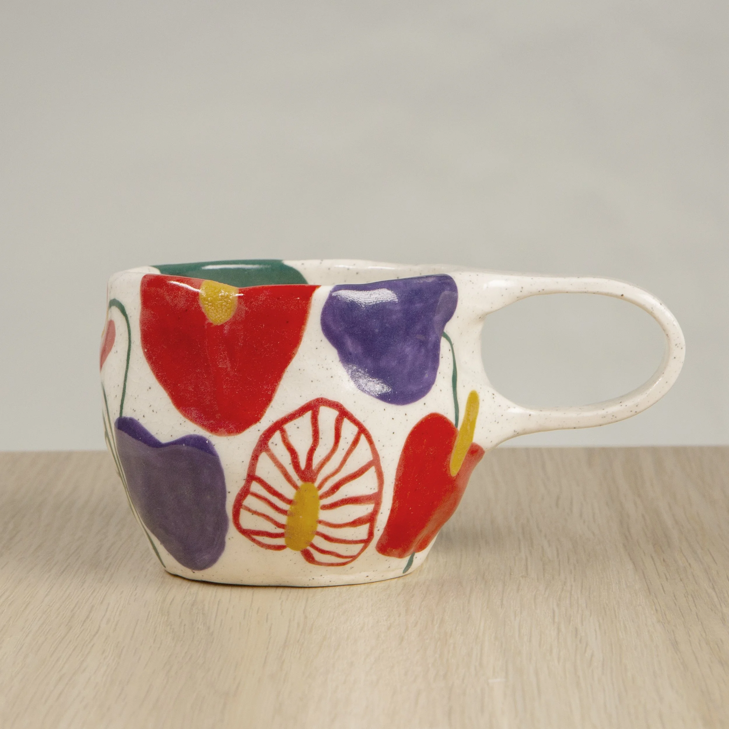 Handmade ceramic coffee cup with hand-painted anthurium flowers, crafted from speckled clay in Melbourne. Holds approximately 150ml.