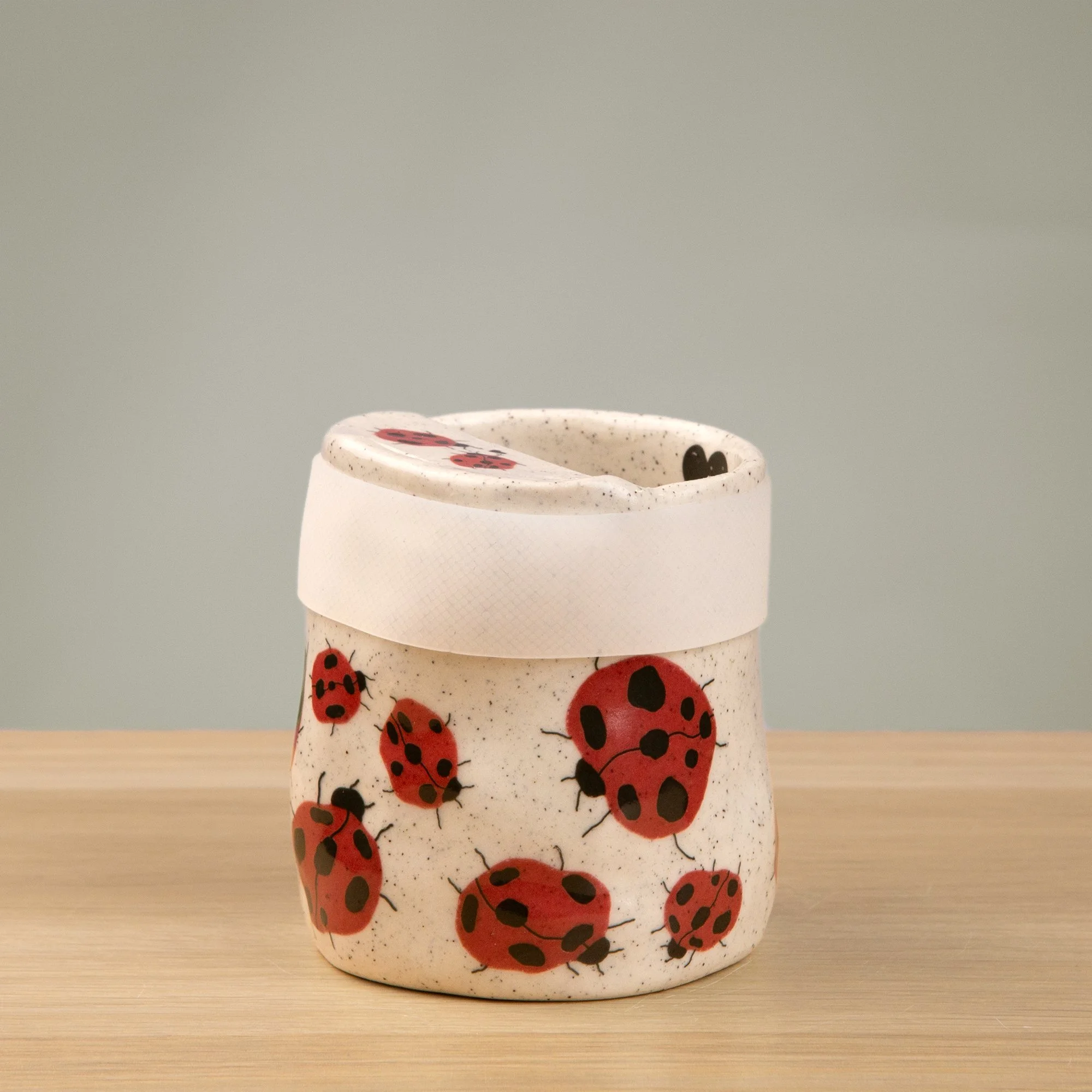 Handmade speckled ceramic Loveliness travel cup decorated with cheerful red ladybugs