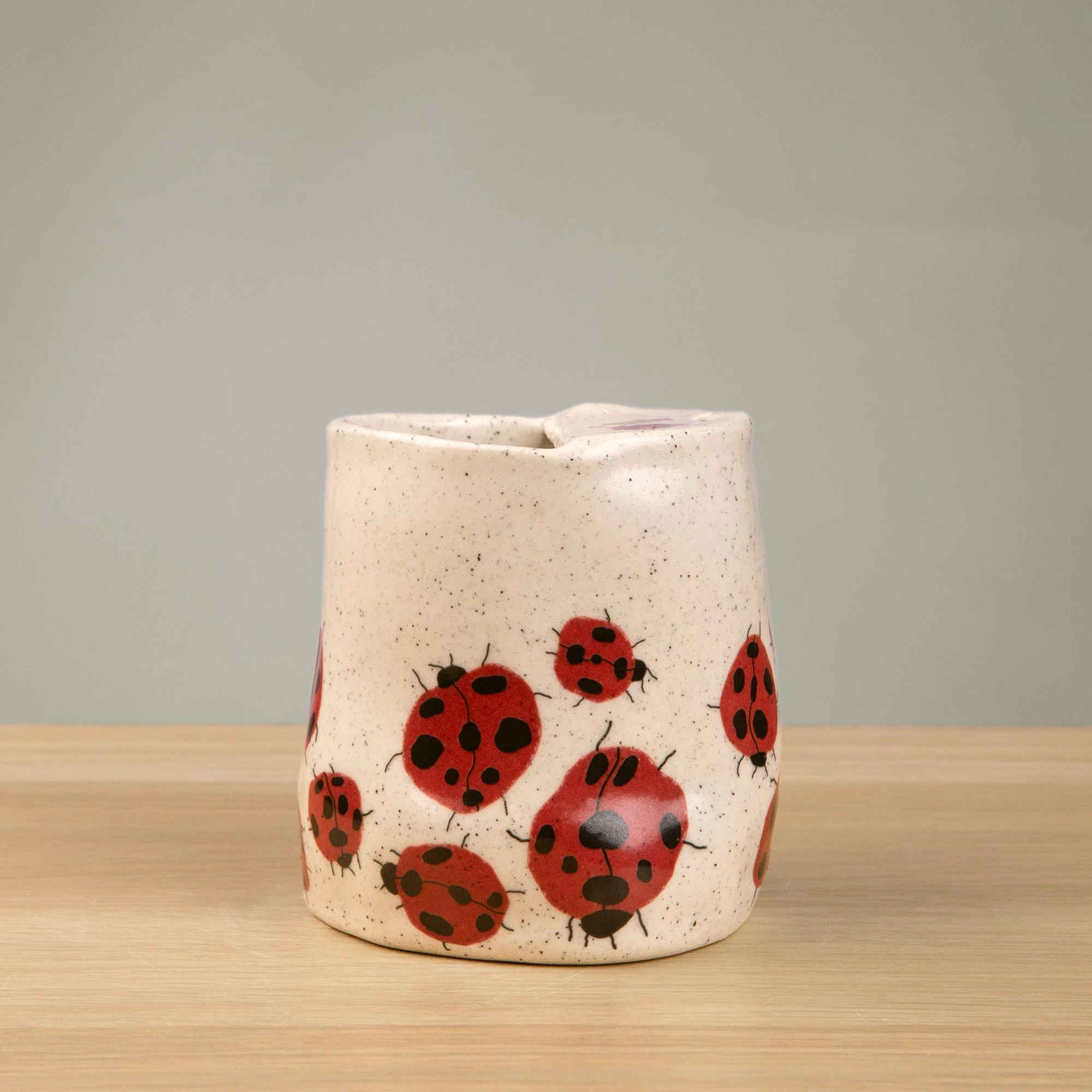 Handmade speckled ceramic Loveliness travel cup decorated with cheerful red ladybugs