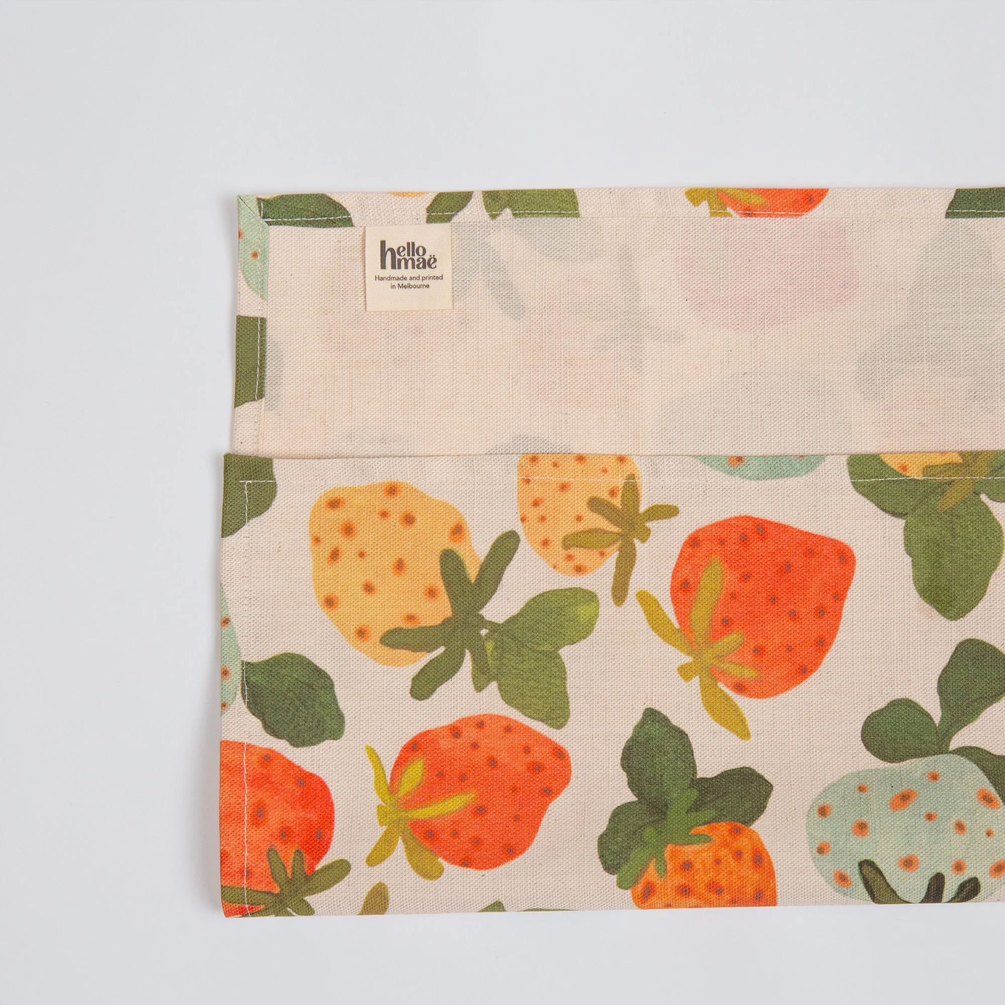 Colourful strawberry tea towel featuring a playful print of yellow, red, pink and blue hand-drawn strawberries.