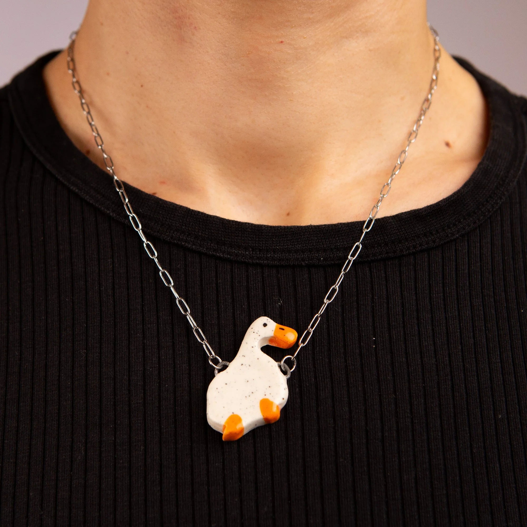 Handmade ceramic duck necklace featuring a playful hand-painted duck pendant on a silver-coloured chain.