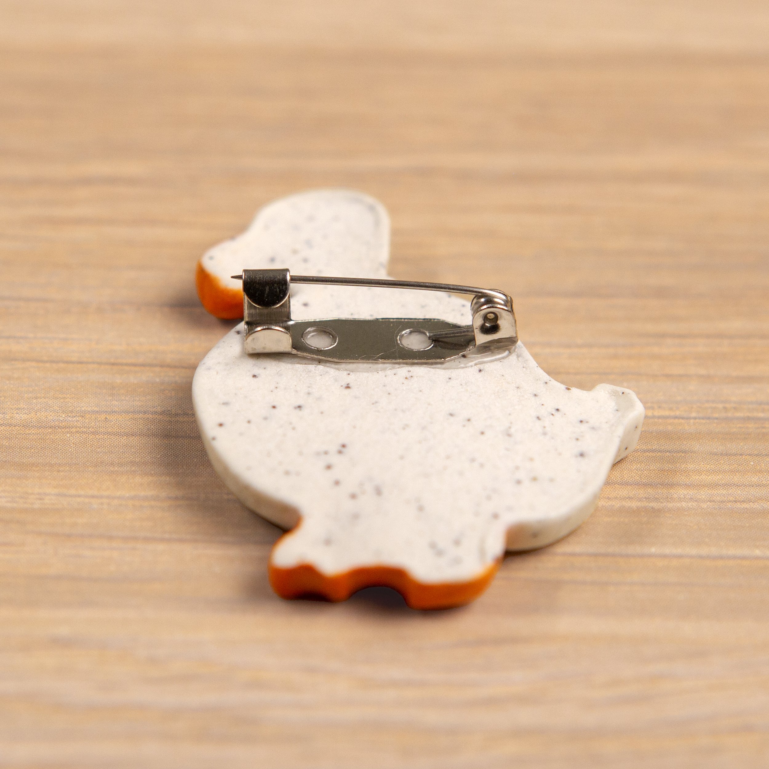 Handmade ceramic brooch with a glossy wandering white duck, photographed on a neutral background. (Copy)