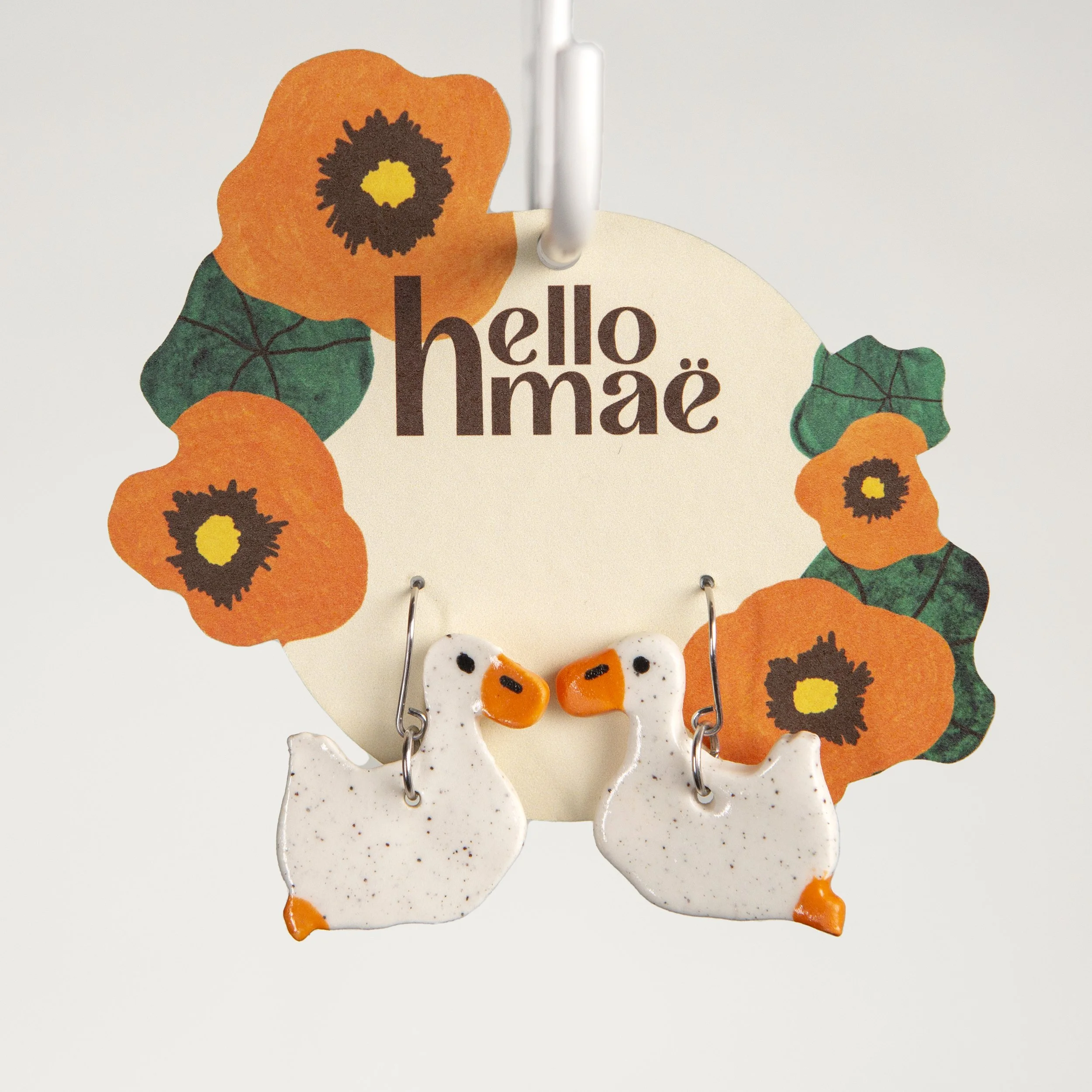 Handmade one-tier ceramic swimming white ducks earrings with surgical steel hooks photographed on a neutral background