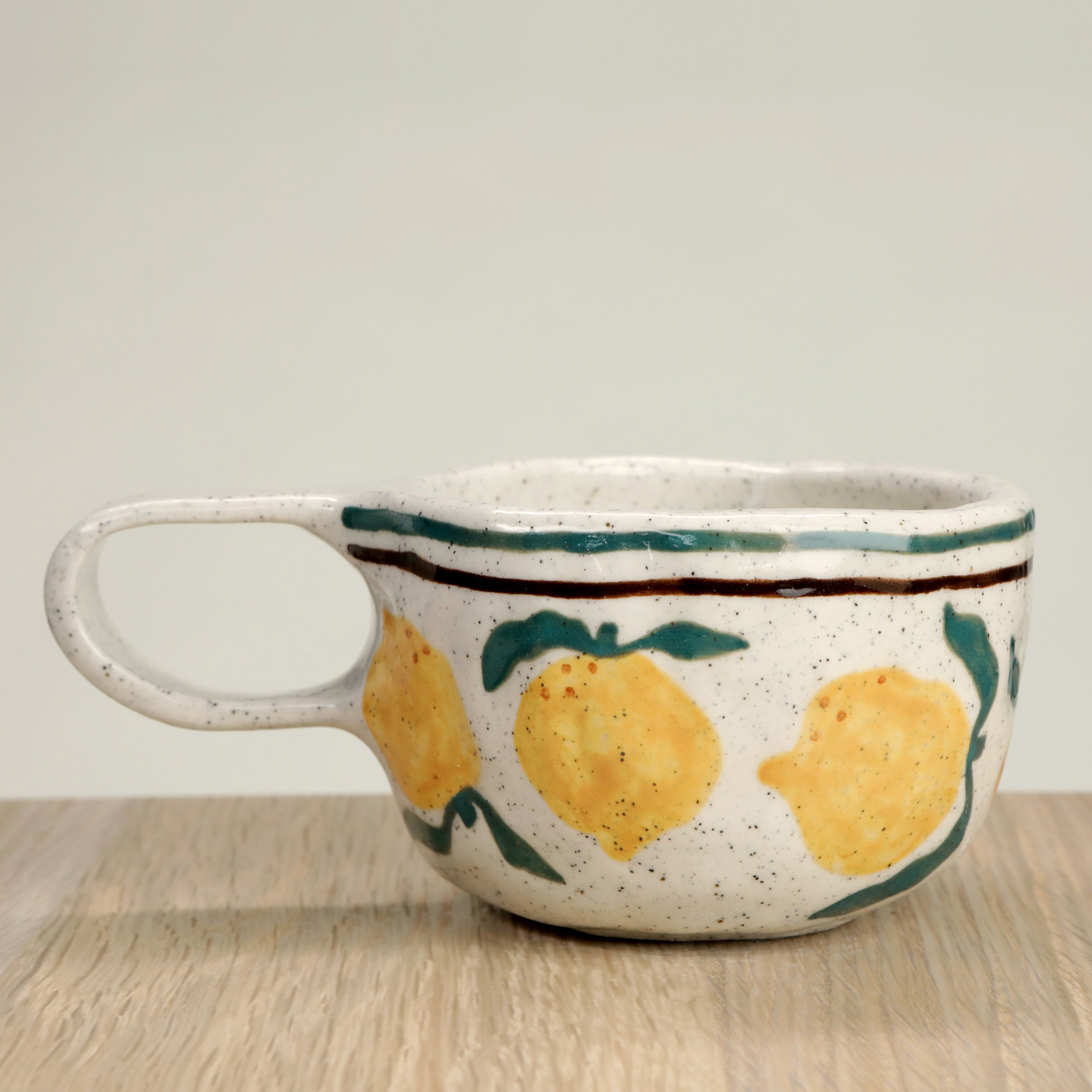 Handmade ceramic coffee cup with hand-painted lemons & 2 lines border, crafted from speckled clay in Melbourne. Holds approximately 150ml.