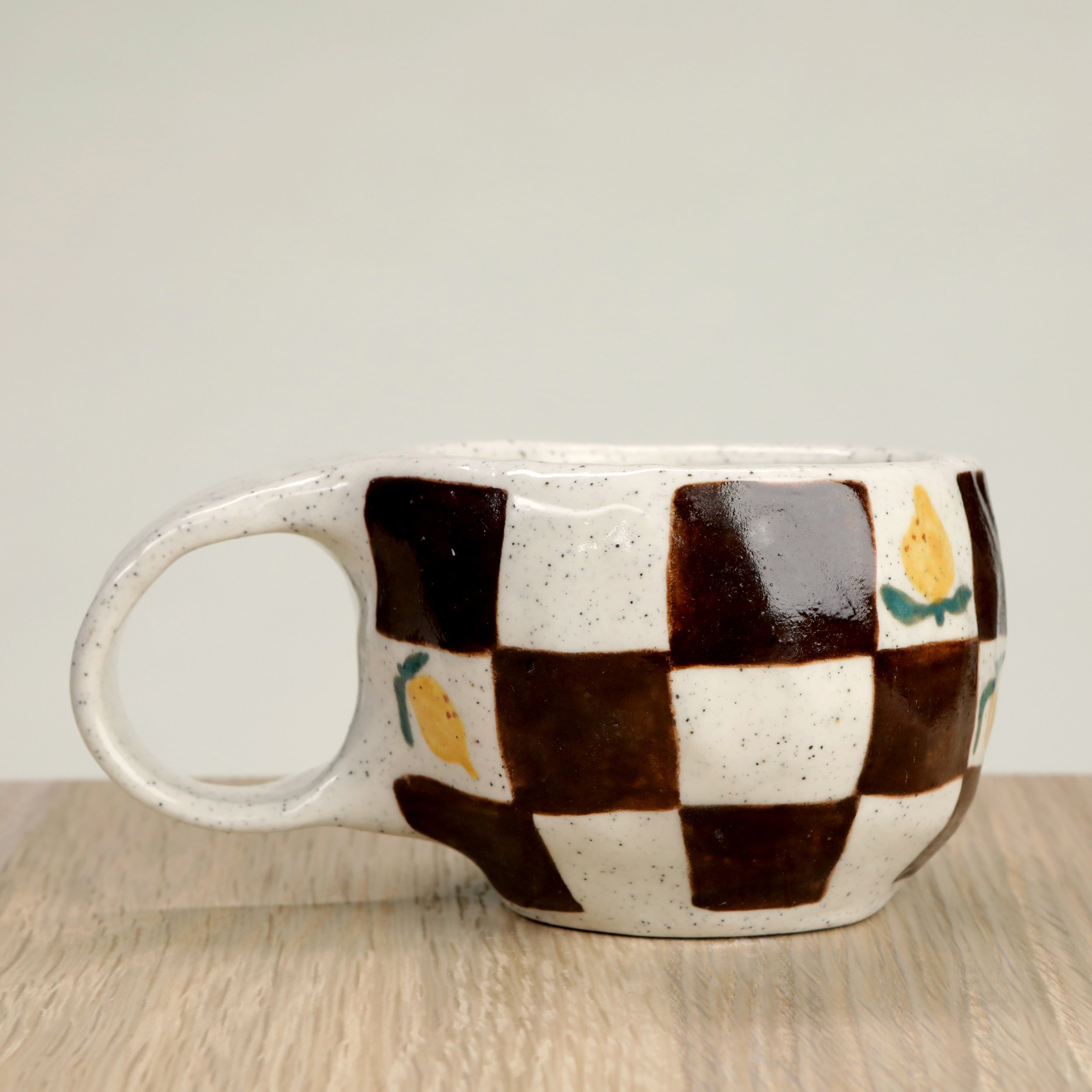 Handmade ceramic coffee cup with hand-painted lemons & a chocolate check, crafted from speckled clay in Melbourne. Holds approximately 150ml.