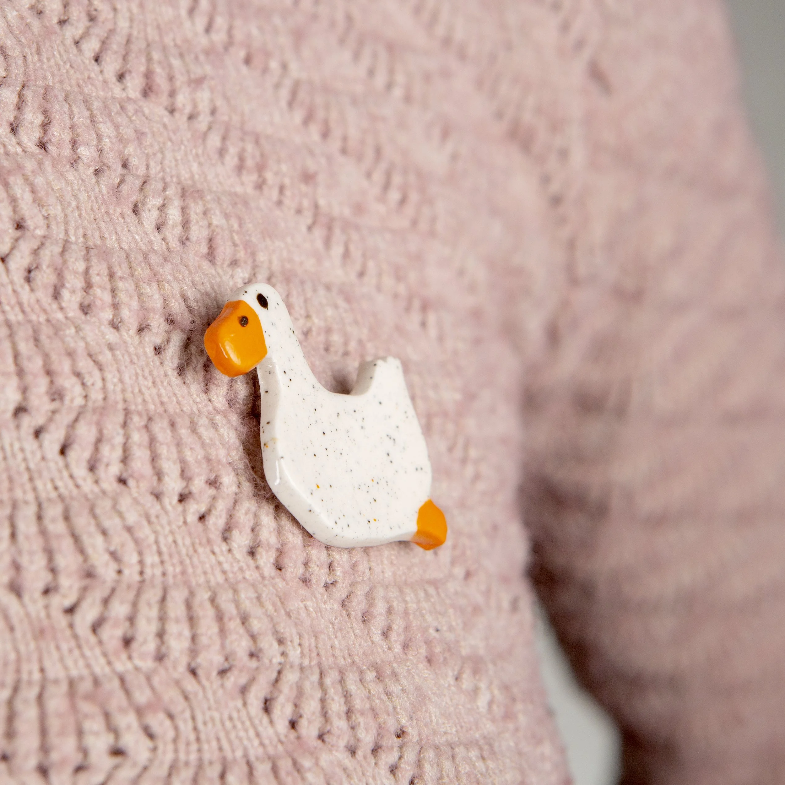 Handmade ceramic brooch with a glossy swimming white duck, photographed on a neutral background