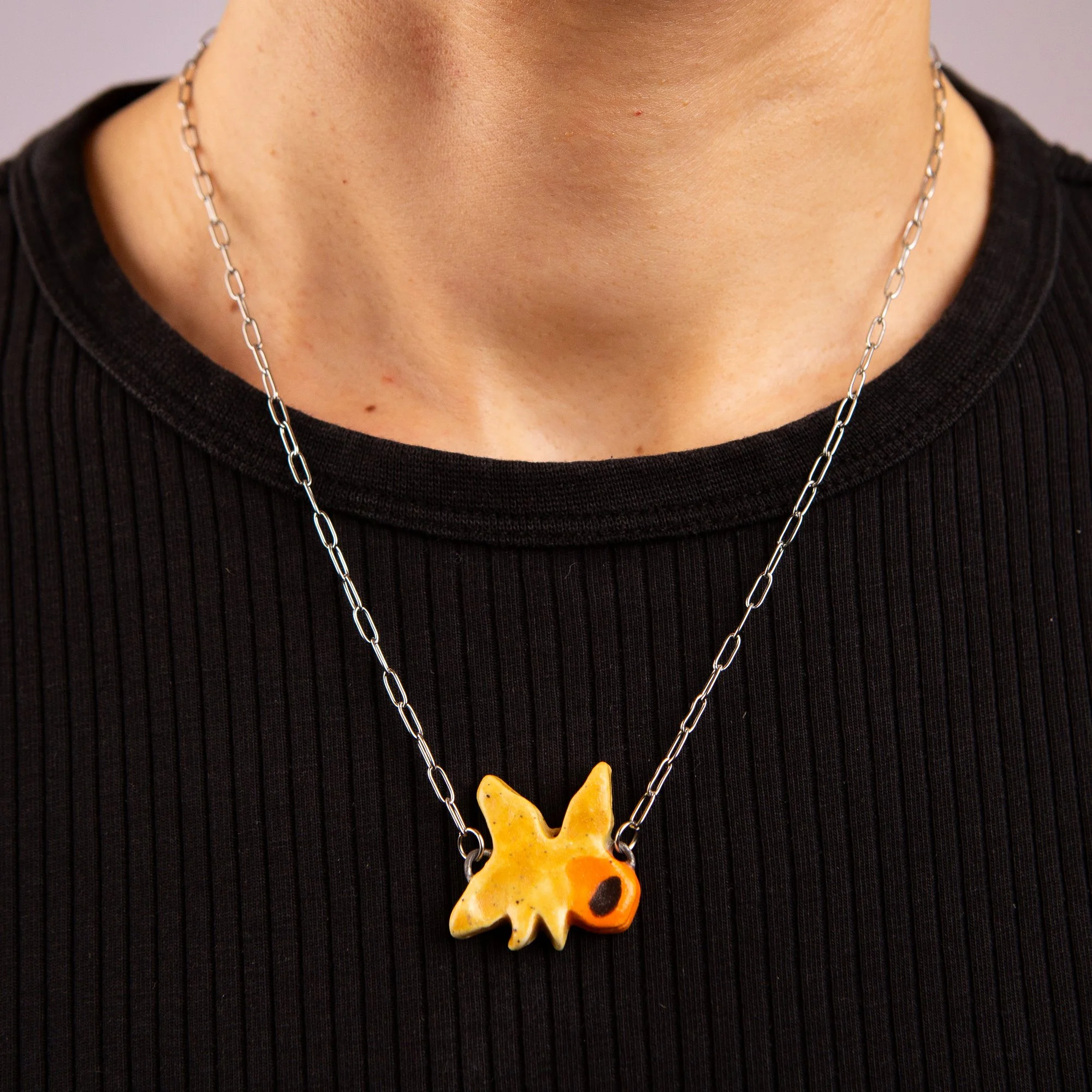 Handmade ceramic daffodil necklace featuring a playful hand-painted daffodil pendant on a silver-coloured chain.