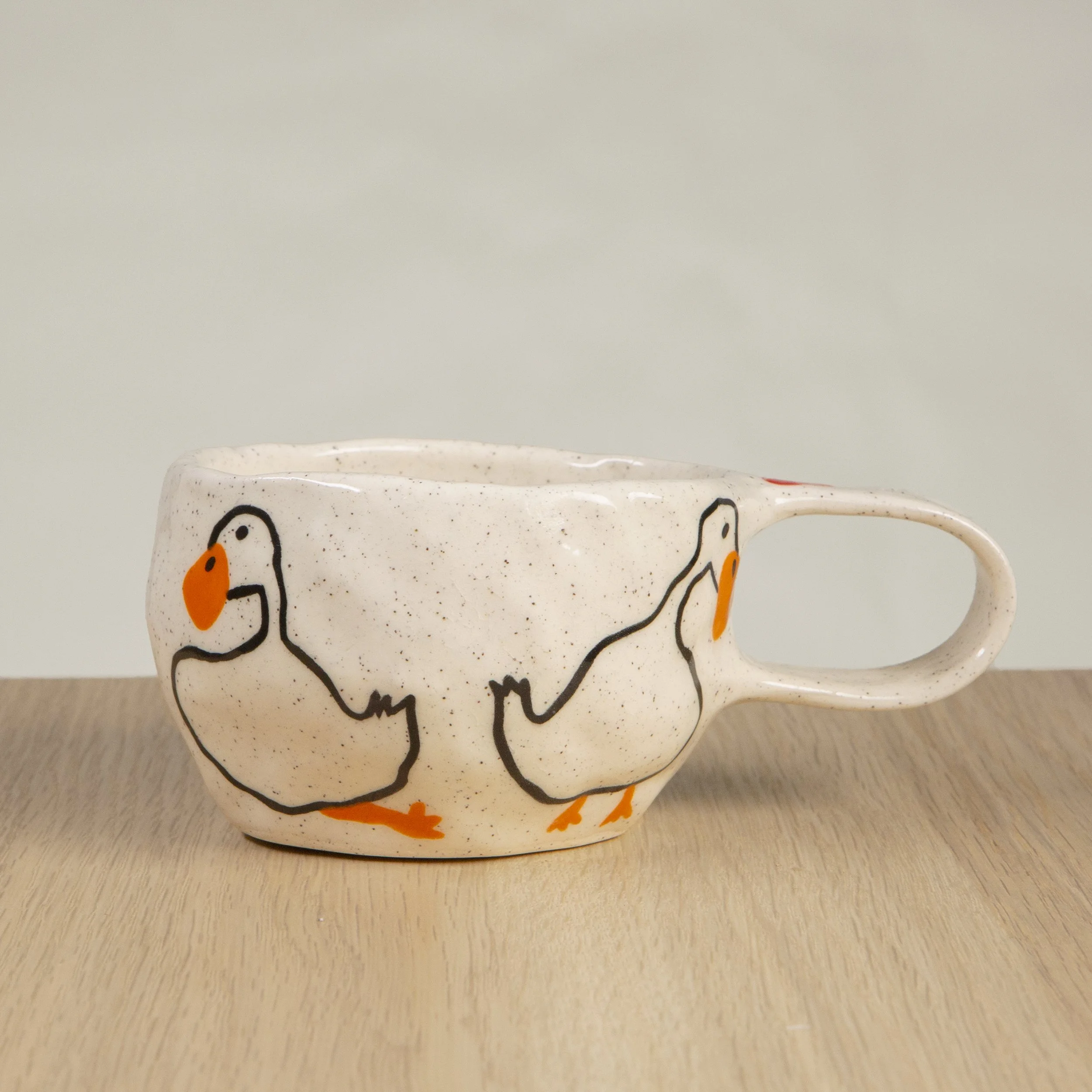 Handmade ceramic coffee cup with hand-painted loving ducks, crafted from speckled clay in Melbourne. Holds approximately 150ml.
